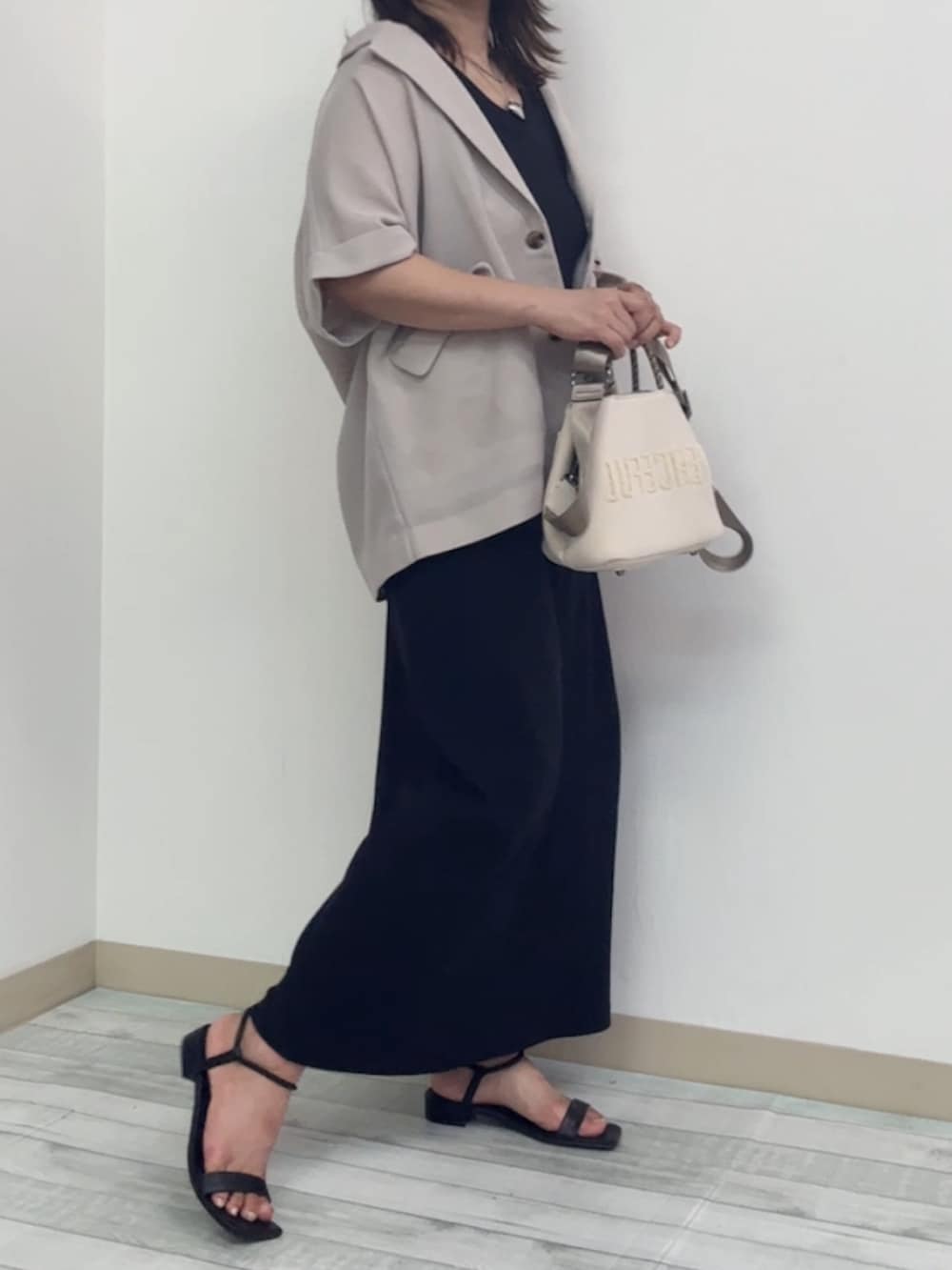 グレー系のテーラードジャケット、ブラック系のサンダル、ブラック系のワンピースを着用したレディースの夏コーディネートの2枚目の写真