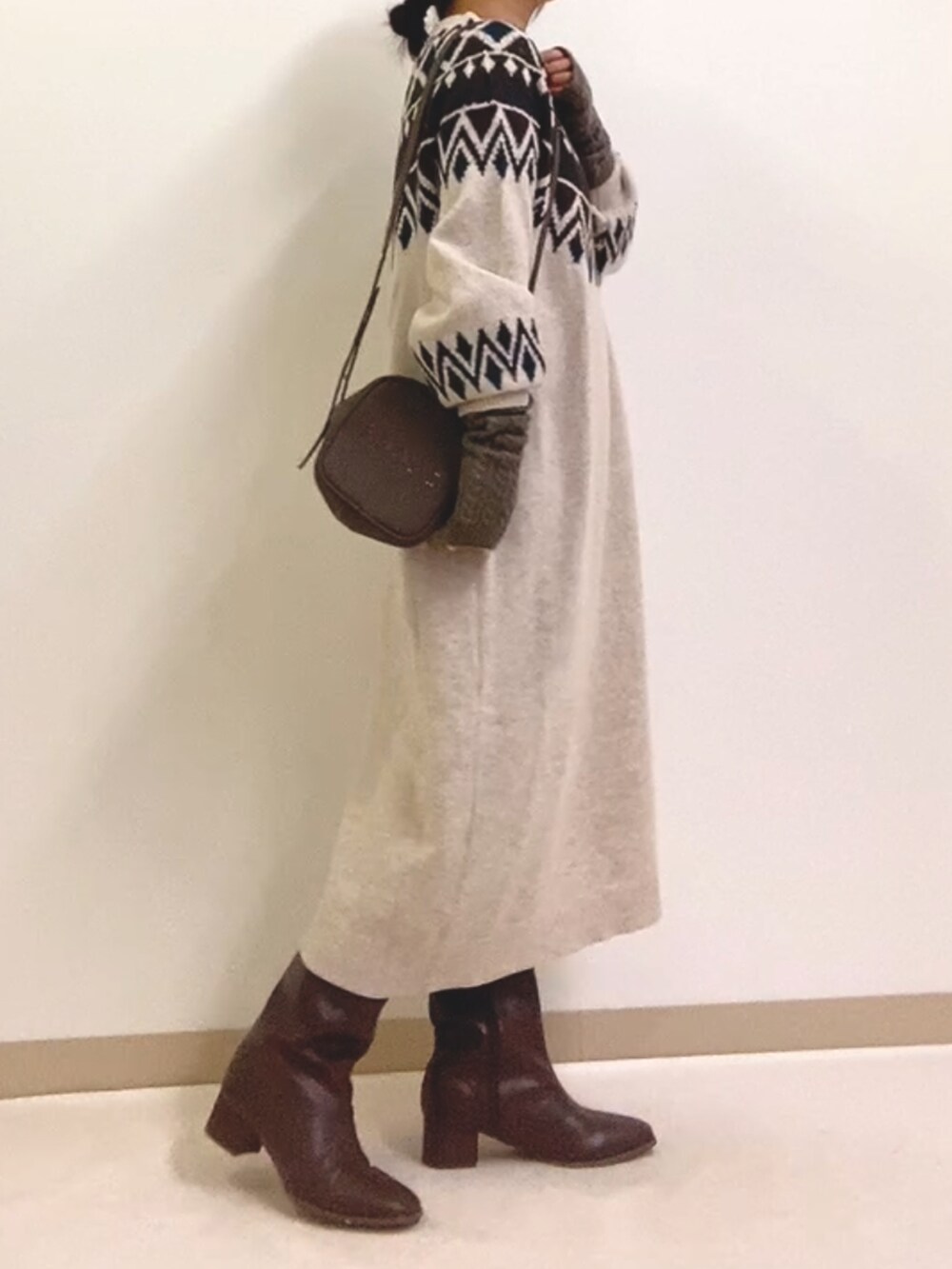 ホワイト系のワンピース、グレー系のショルダーバッグ、ブラウン系のブーツを着用したレディースの冬コーディネートの2枚目の写真