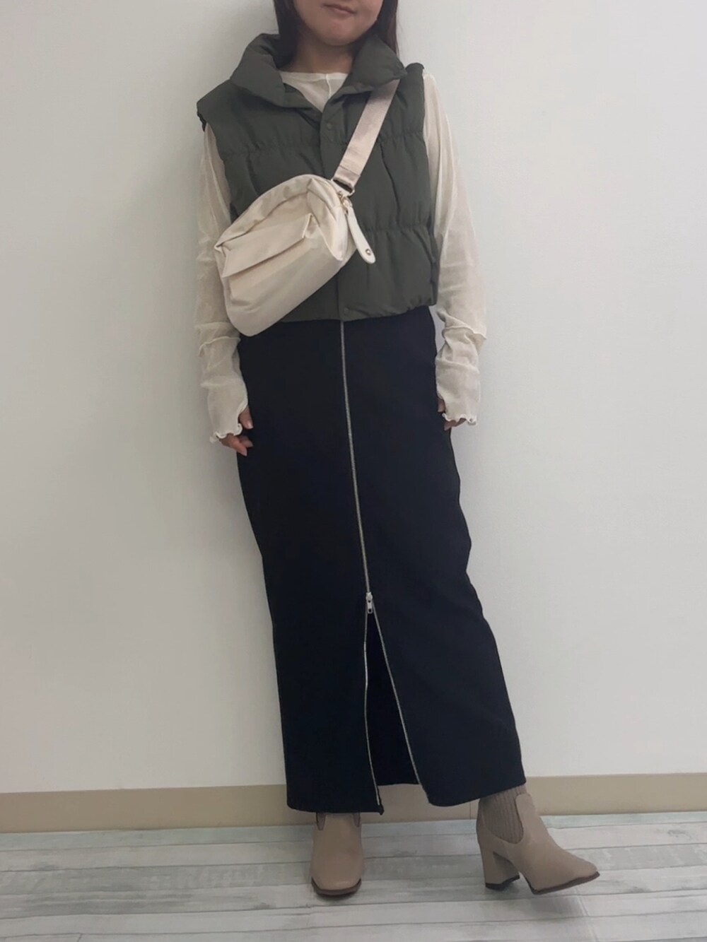 ブラック系のスカート、ベージュ系のブーツ、ホワイト系のショルダーバッグを着用したレディースの秋コーディネートの3枚目の写真