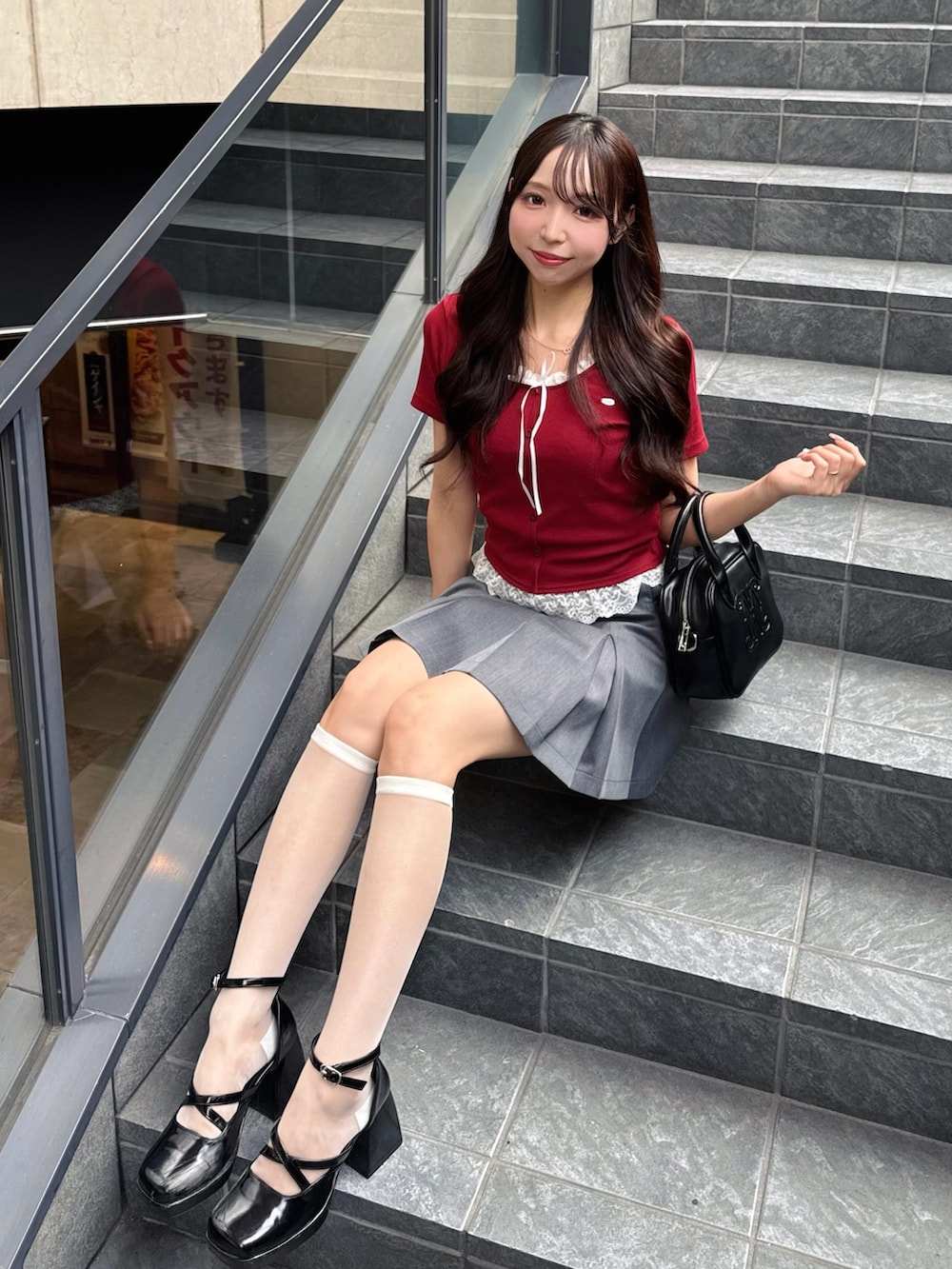 レッド系のTシャツ/カットソー、グレー系のスカート、ブラック系のハンドバッグを着用したレディースの夏コーディネートの3枚目の写真