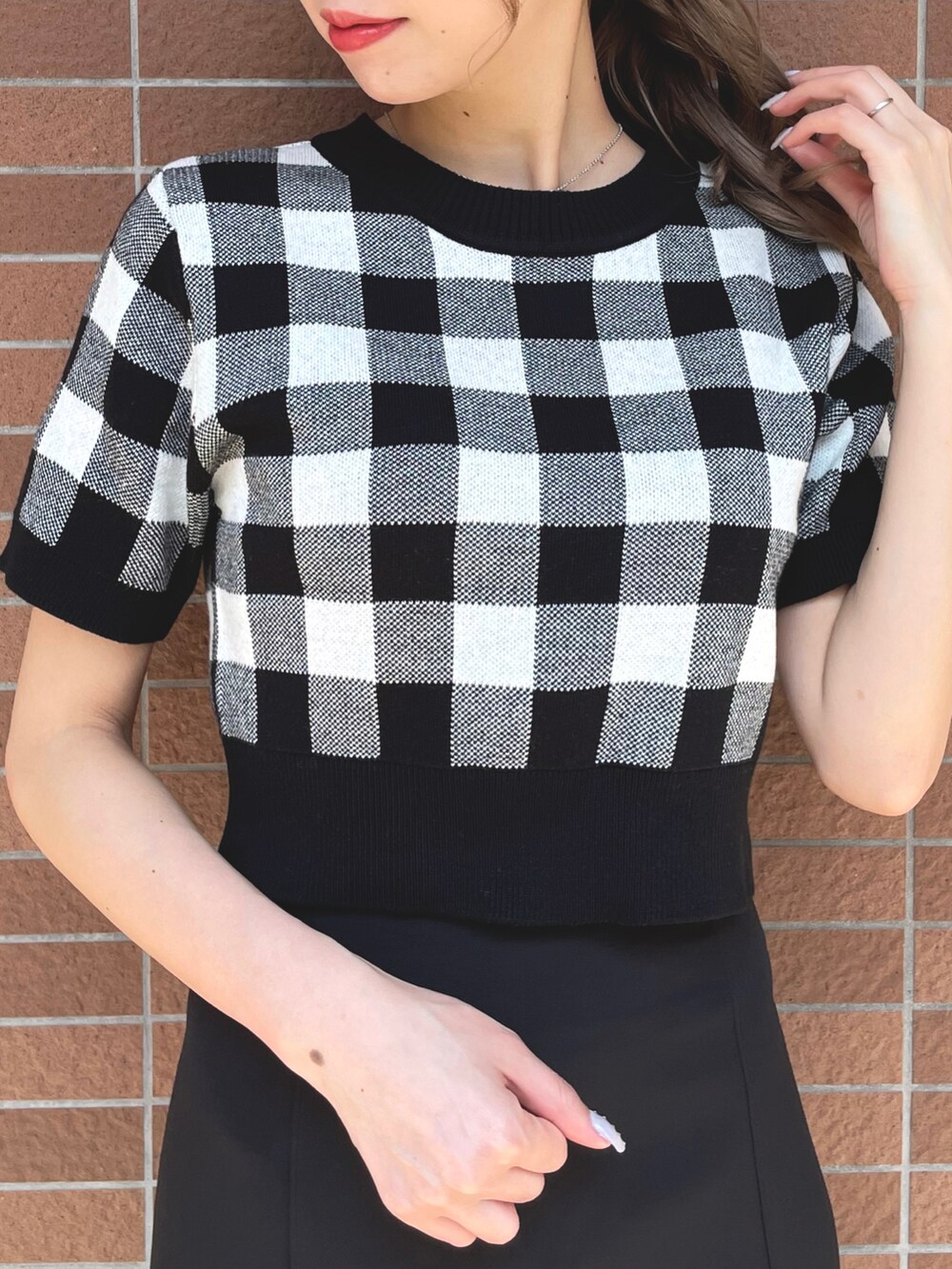 ブラック系のニット/セーター、ブラック系のスカートを着用したレディースの夏コーディネートの2枚目の写真