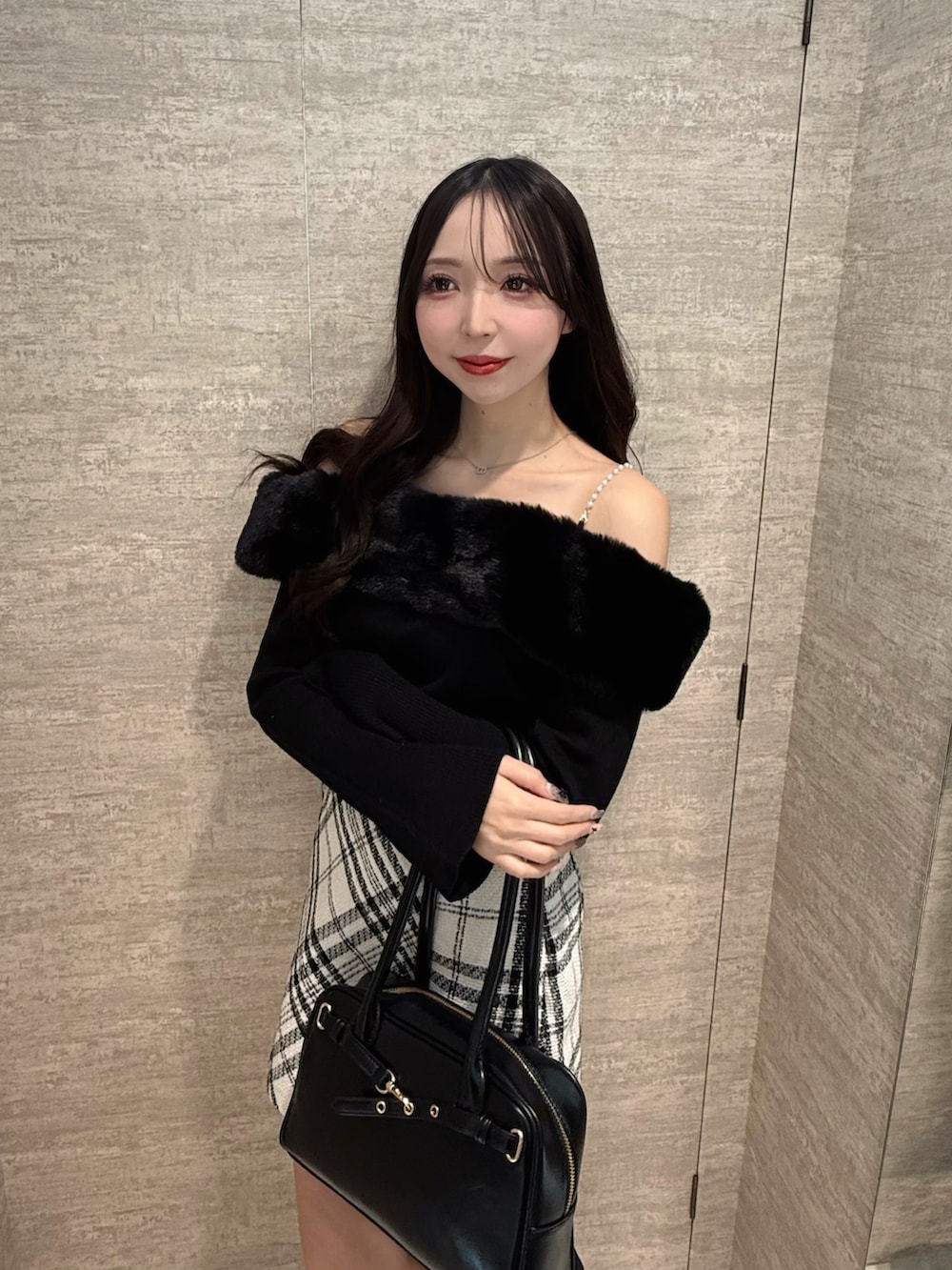 ブラック系のニット/セーター、ホワイト系のスカート、ブラック系のハンドバッグを着用したレディースの秋コーディネートの3枚目の写真