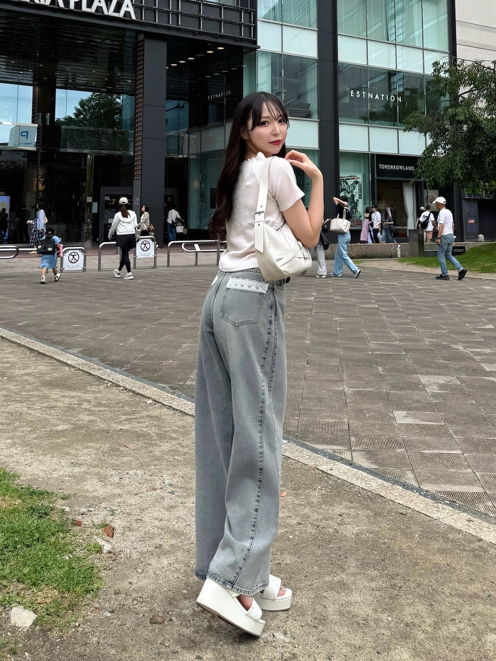 ブルー系のデニムパンツ、ピンク系のTシャツ/カットソー、ホワイト系のハンドバッグを着用したレディースの夏コーディネートの4枚目の写真