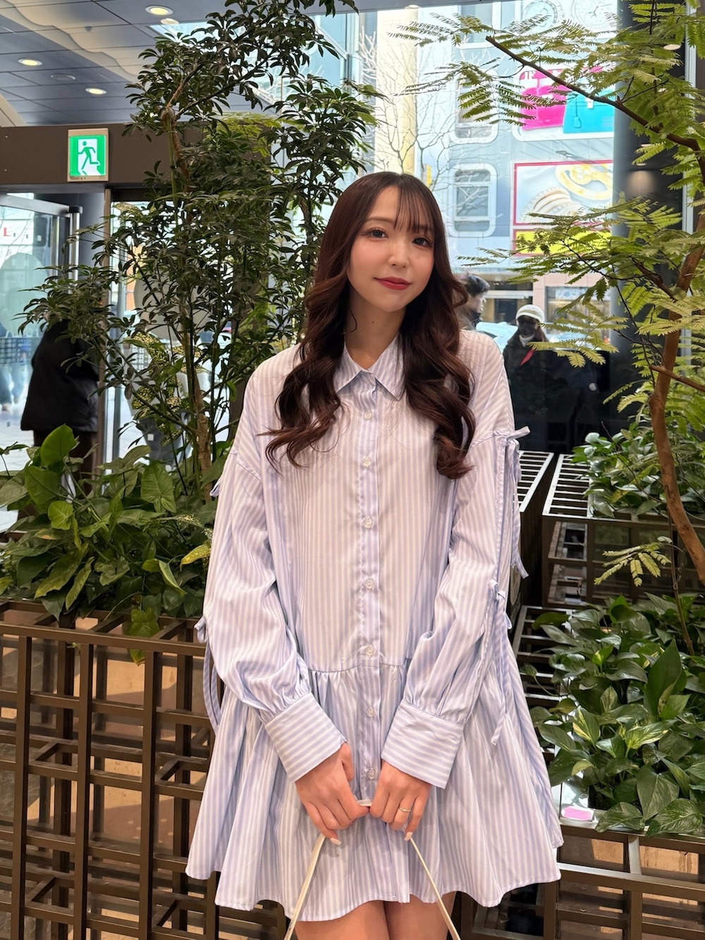 ブルー系のシャツワンピース、ホワイト系のハンドバッグ、ブラック系のブーツを着用したレディースの春コーディネートの2枚目の写真