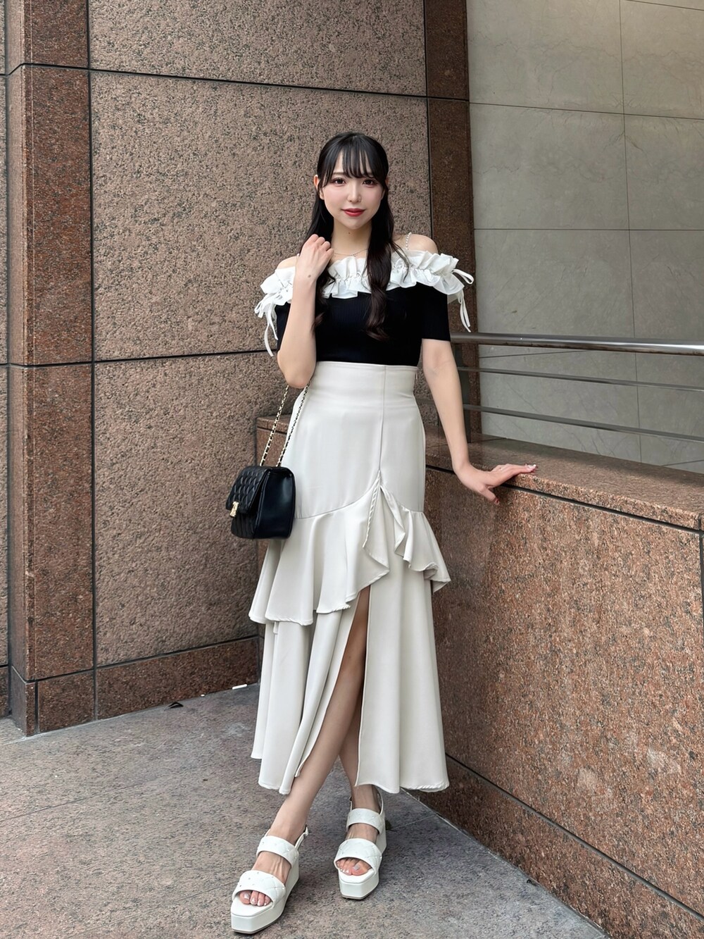 ブラック系のニット/セーター、ベージュ系のスカート、ブラック系のショルダーバッグを着用したレディースの夏コーディネートの4枚目の写真