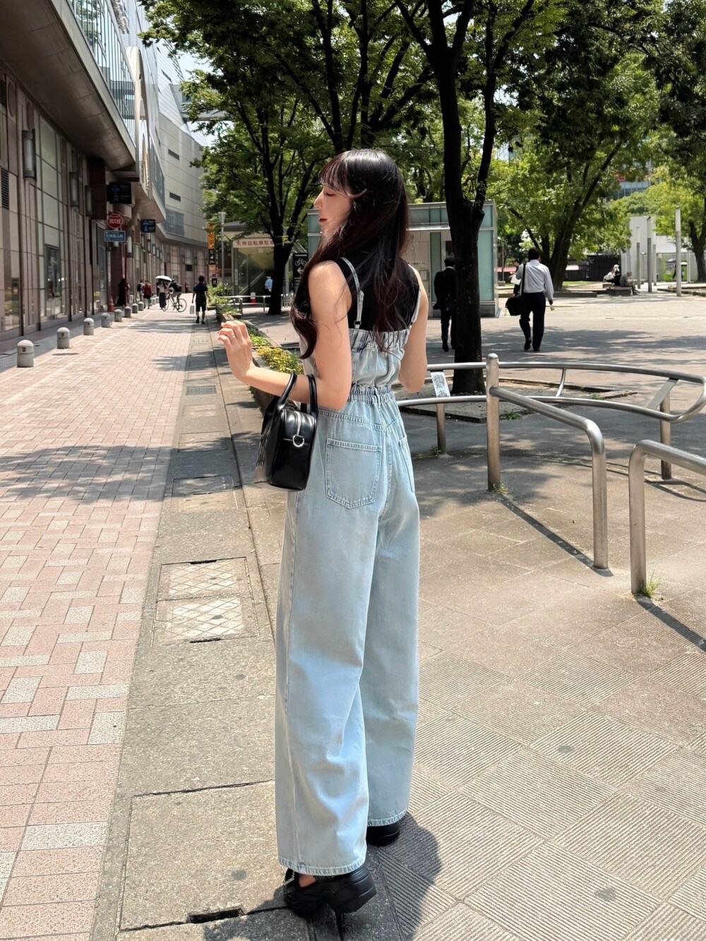 ブルー系のサロペット/オーバーオール、ブラック系のハンドバッグ、ブラック系のサンダルを着用したレディースの夏コーディネートの3枚目の写真