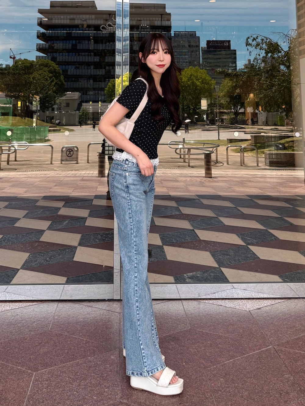 ブルー系のデニムパンツ、ホワイト系のサンダル、ホワイト系のハンドバッグを着用したレディースの夏コーディネートの2枚目の写真