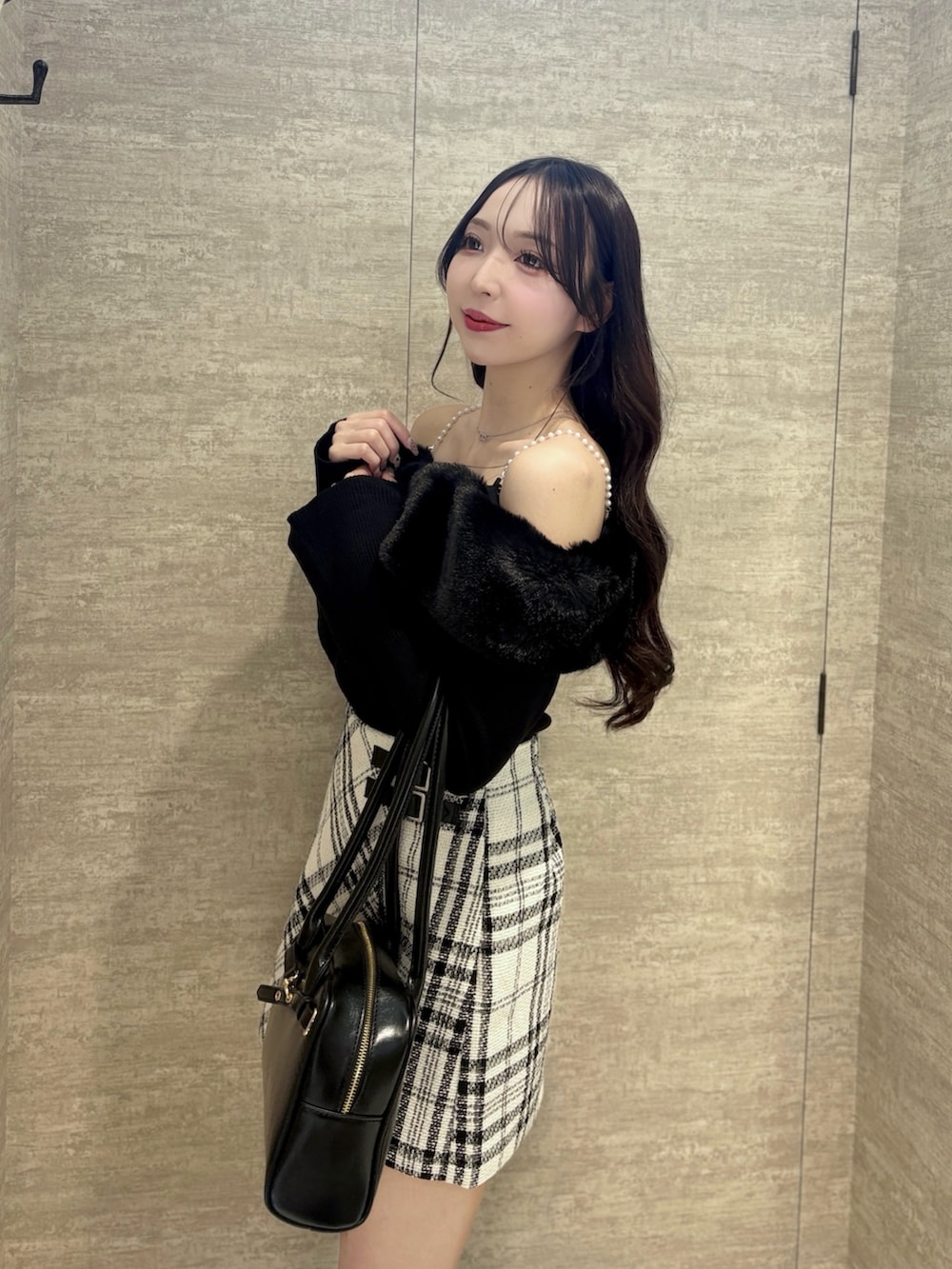 ブラック系のニット/セーター、ホワイト系のスカート、ブラック系のハンドバッグを着用したレディースの秋コーディネートの4枚目の写真