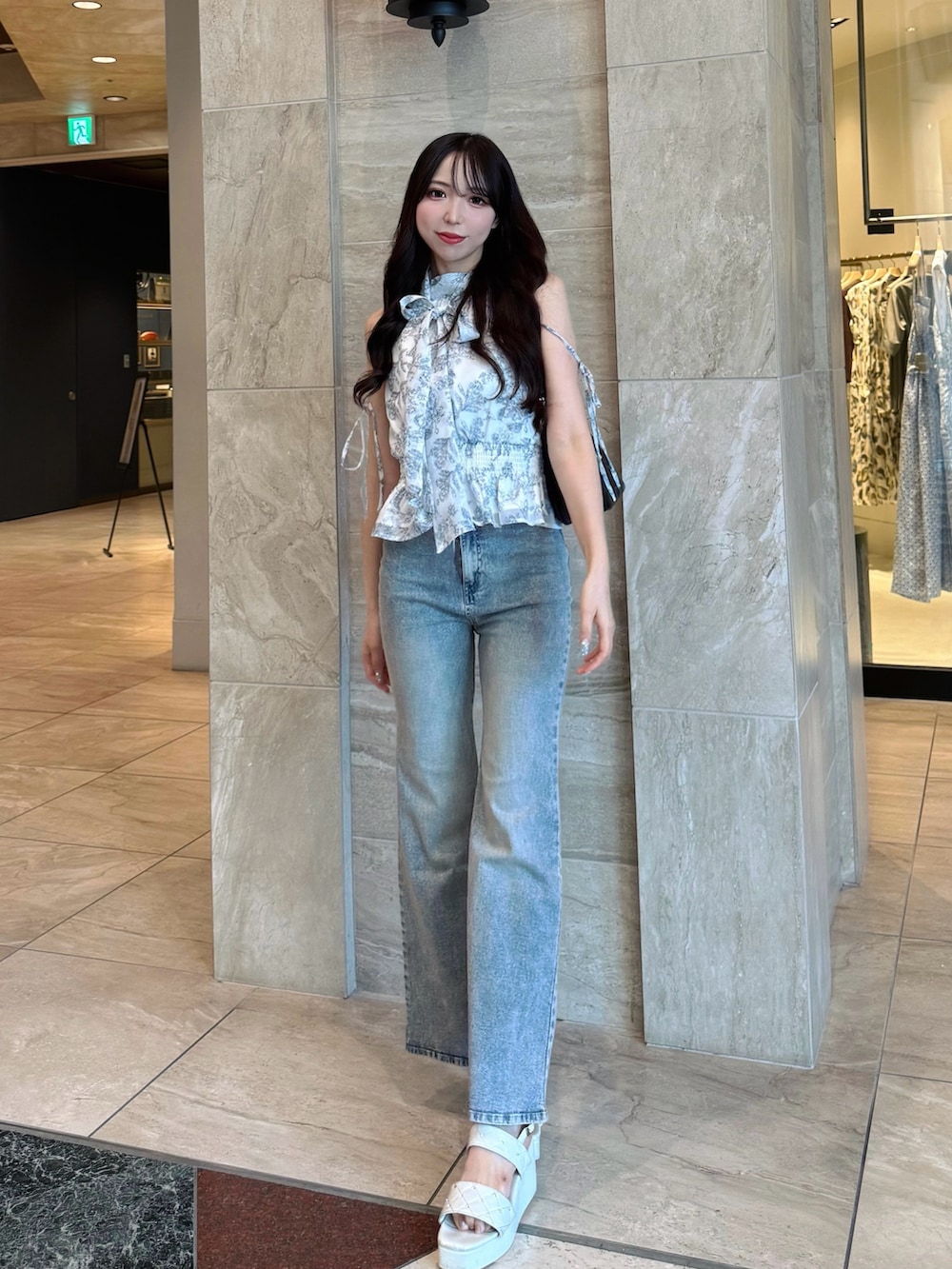 ブルー系のデニムパンツ、ホワイト系のシャツ/ブラウス、ホワイト系のサンダルを着用したレディースの夏コーディネートの3枚目の写真