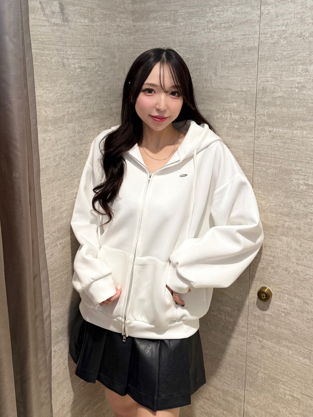 ホワイト系のパーカー、ブラック系のスカート、ベージュ系のブーツを着用したレディースの秋コーディネートの2枚目の写真