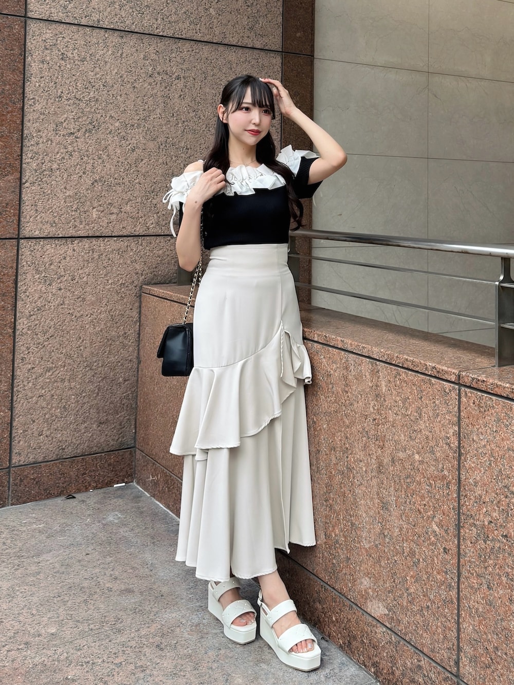 ブラック系のニット/セーター、ベージュ系のスカート、ブラック系のショルダーバッグを着用したレディースの夏コーディネートの3枚目の写真