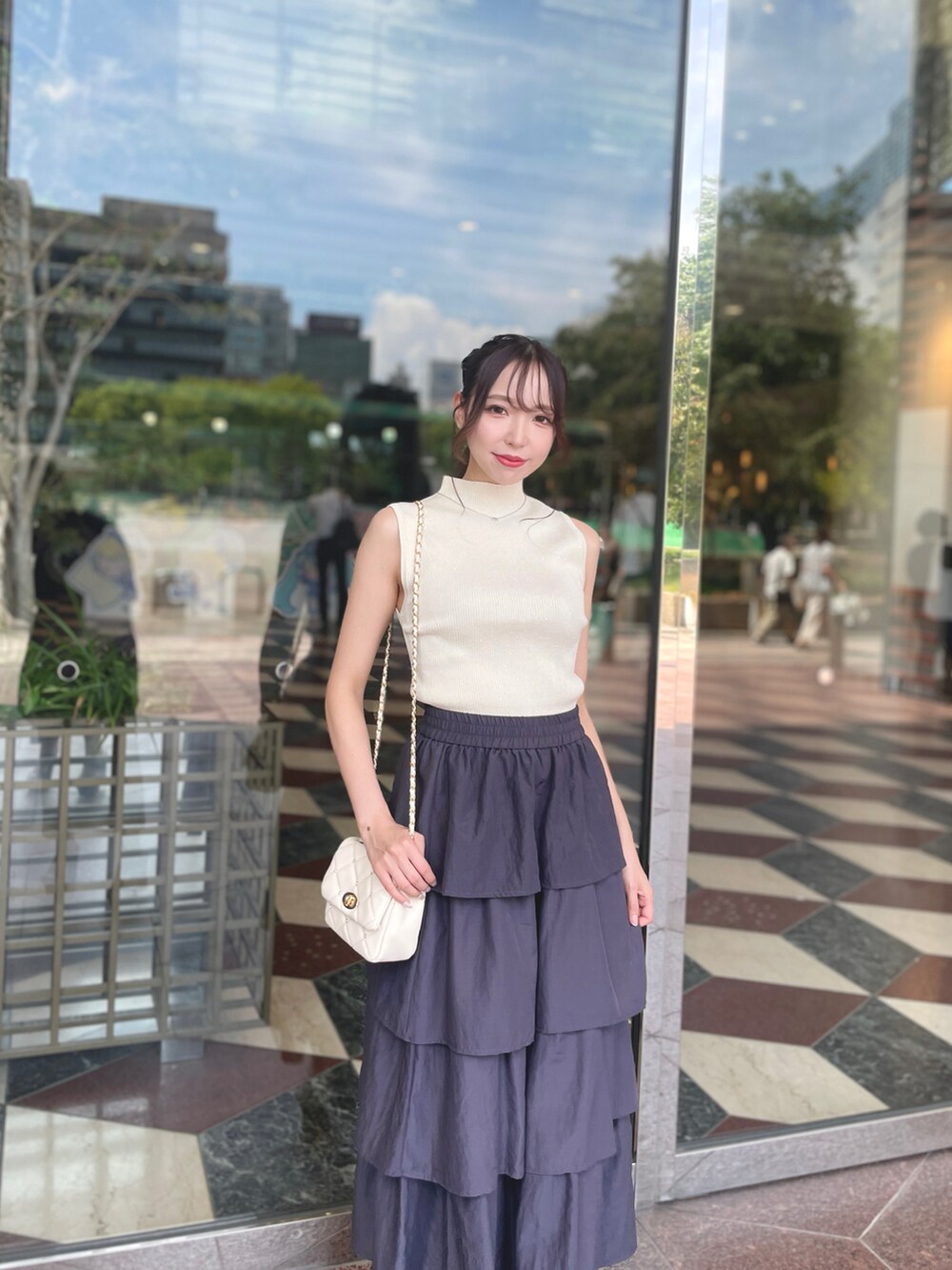 ホワイト系のニット/セーター、ホワイト系のショルダーバッグ、グレー系のスカートを着用したレディースの夏コーディネートの3枚目の写真