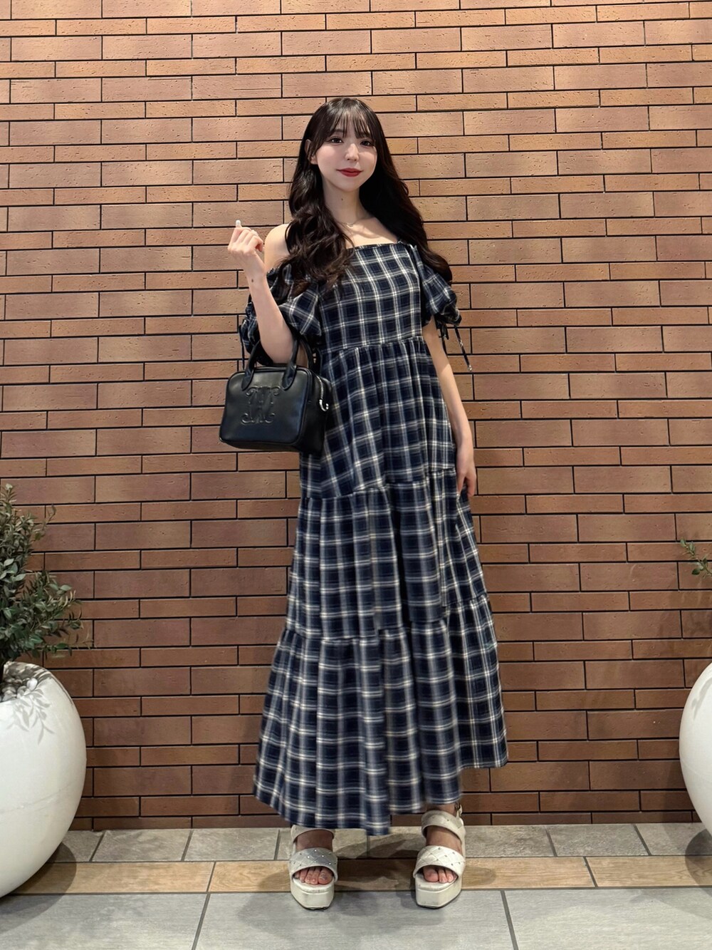 ブルー系のワンピース、ブラック系のハンドバッグ、ホワイト系のサンダルを着用したレディースの夏コーディネートの4枚目の写真