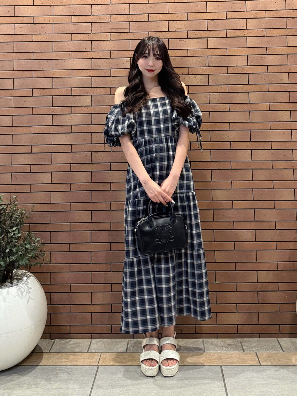 ブルー系のワンピース、ブラック系のハンドバッグ、ホワイト系のサンダルを着用したレディースの夏コーディネートの3枚目の写真