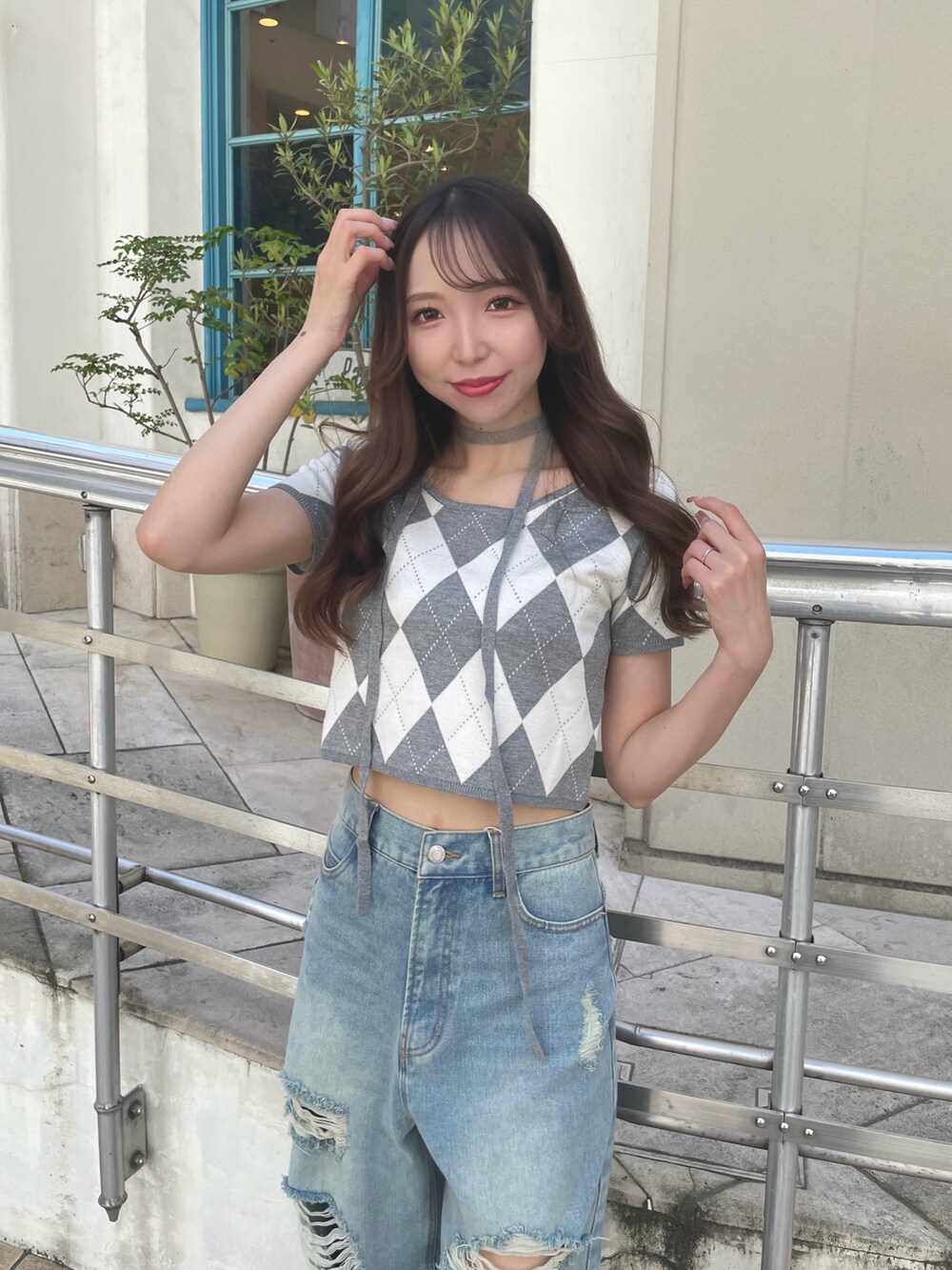 グレー系のニット/セーター、ブルー系のデニムパンツ、ブラック系のショルダーバッグを着用したレディースの夏コーディネートの2枚目の写真