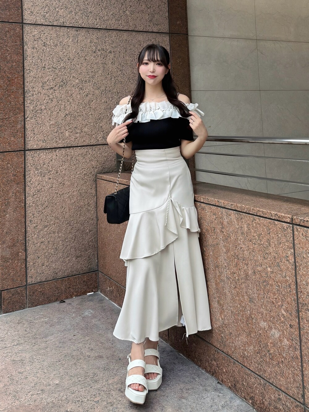 ブラック系のニット/セーター、ベージュ系のスカート、ブラック系のショルダーバッグを着用したレディースの夏コーディネートの2枚目の写真