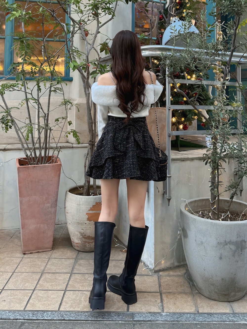 ブラック系のブーツ、ブラック系のショルダーバッグ、ブラック系のスカートを着用したレディースの秋コーディネートの3枚目の写真