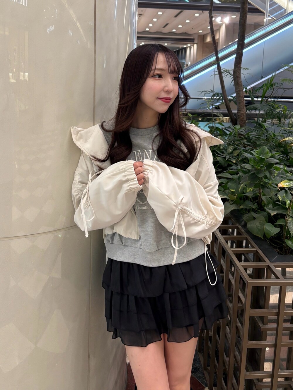 ホワイト系のマウンテンパーカー、グレー系のスウェット、ブラック系のスカートを着用したレディースの春コーディネートの2枚目の写真