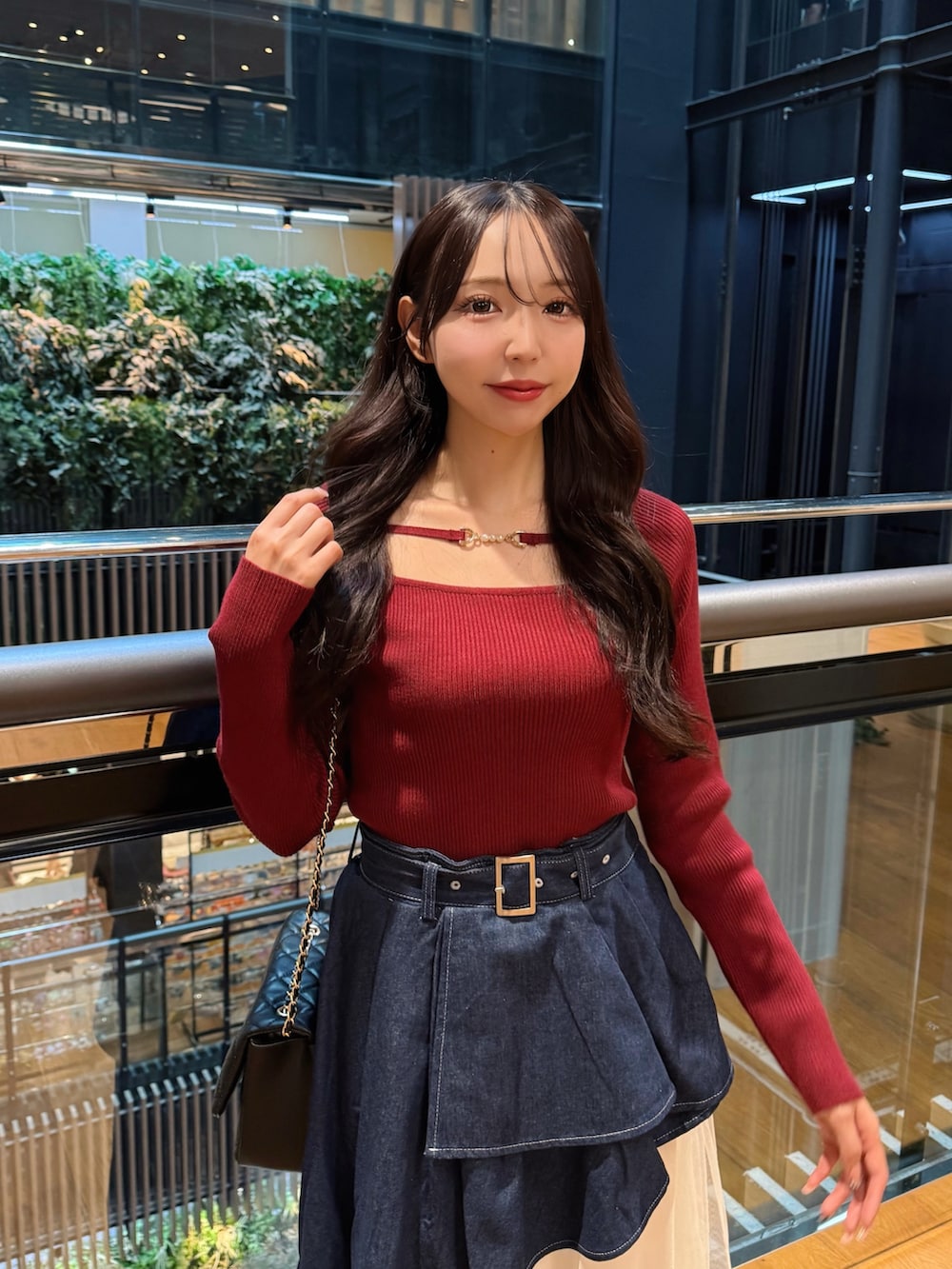 レッド系のニット/セーター、ブルー系のスカート、ブラック系のショルダーバッグを着用したレディースの秋コーディネートの5枚目の写真