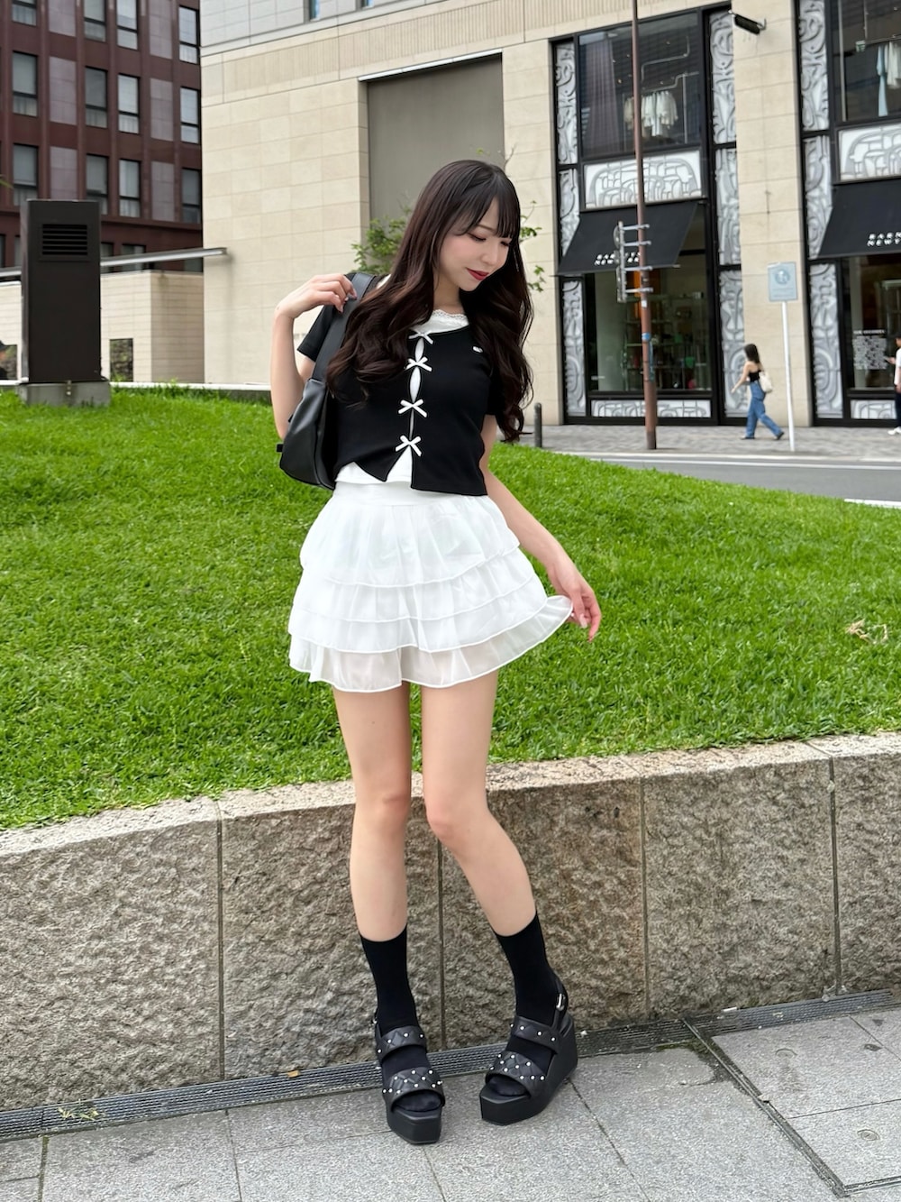 ブラック系のTシャツ/カットソー、ホワイト系のスカート、ブラック系のサンダルを着用したレディースの夏コーディネートの2枚目の写真