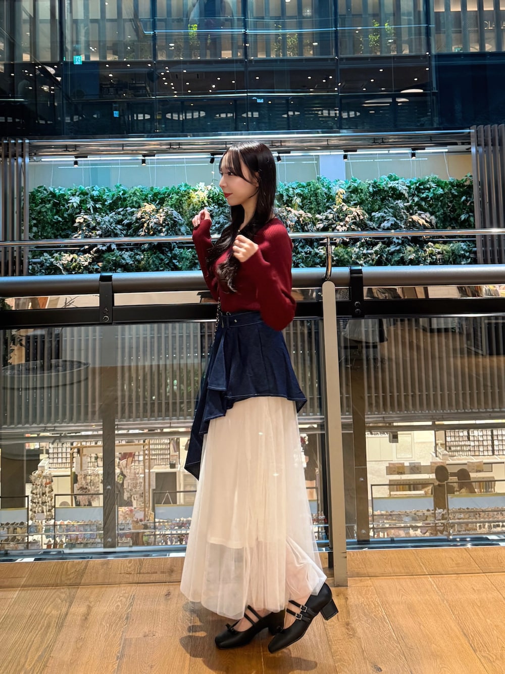 レッド系のニット/セーター、ブルー系のスカート、ブラック系のショルダーバッグを着用したレディースの秋コーディネートの2枚目の写真