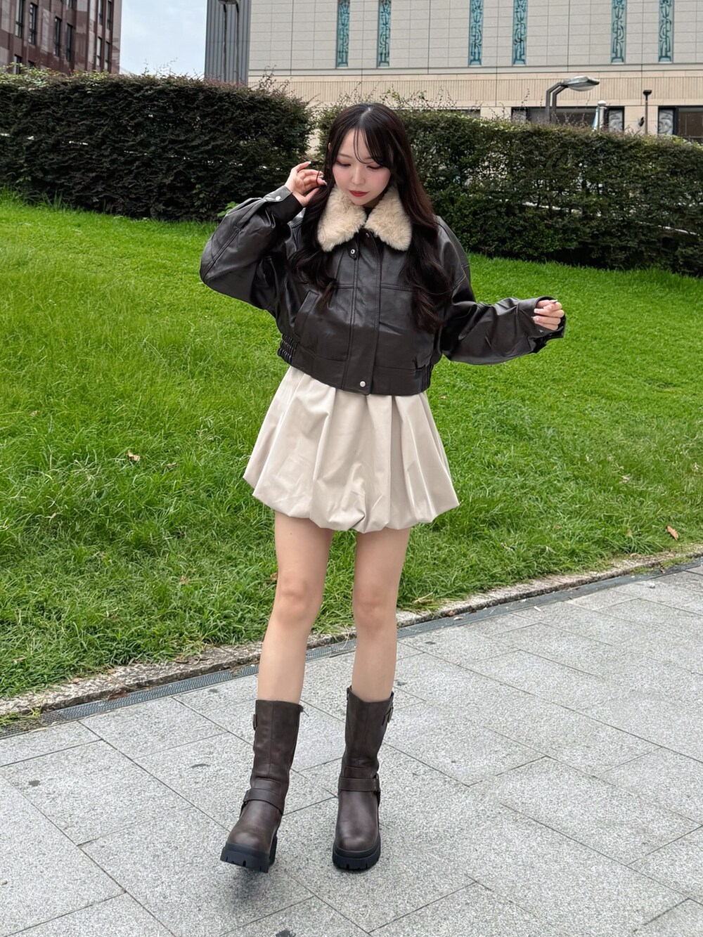 ブラック系のブルゾン、ベージュ系のスカート、ブラウン系のブーツを着用したレディースの秋コーディネートの3枚目の写真