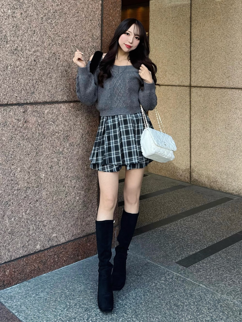 グレー系のニット/セーター、ホワイト系のショルダーバッグ、ブラック系のスカートを着用したレディースの秋コーディネートの4枚目の写真