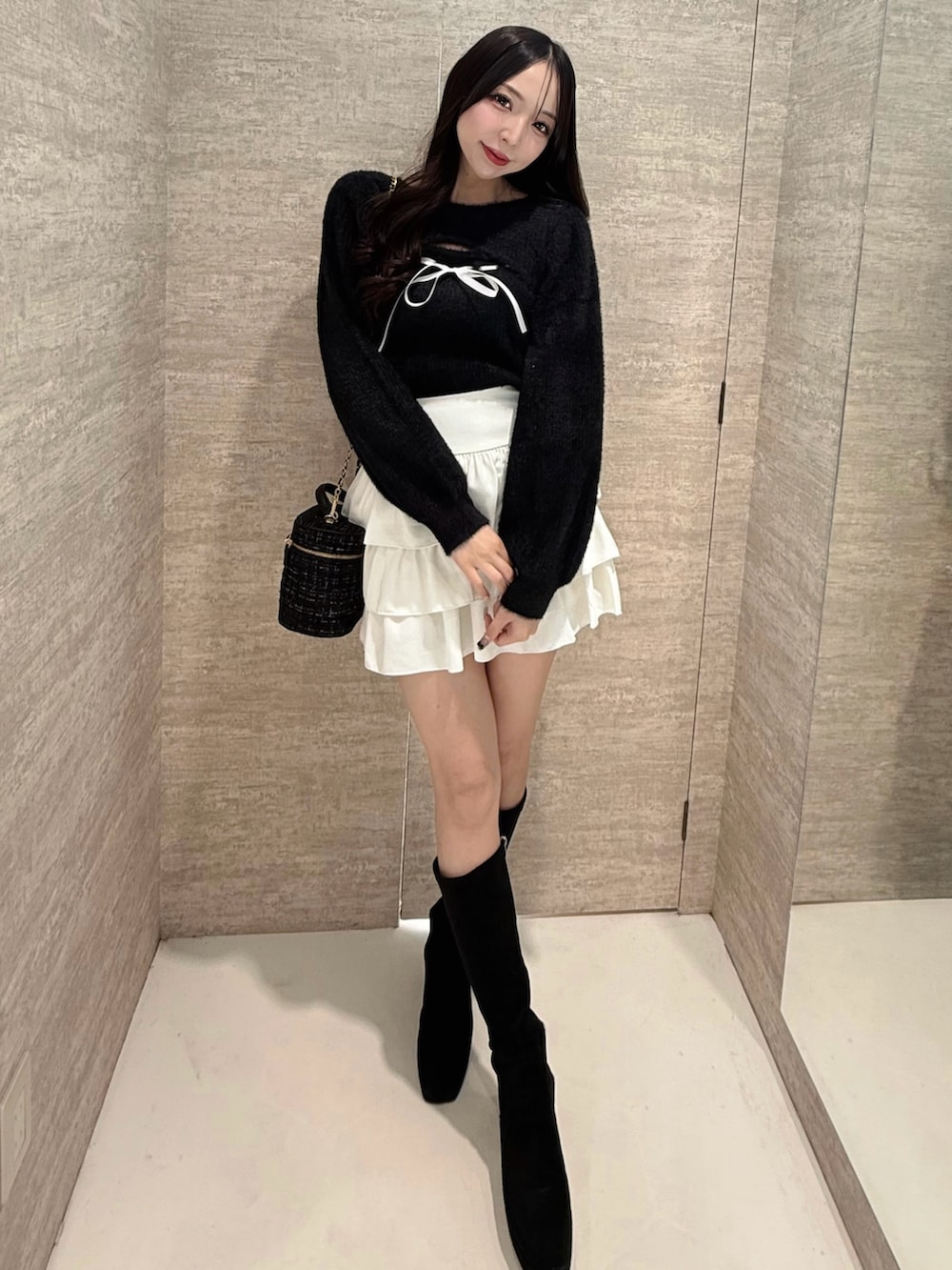 ブラック系のニット/セーター、ホワイト系のスカート、ブラック系のショルダーバッグを着用したレディースの秋コーディネートの3枚目の写真