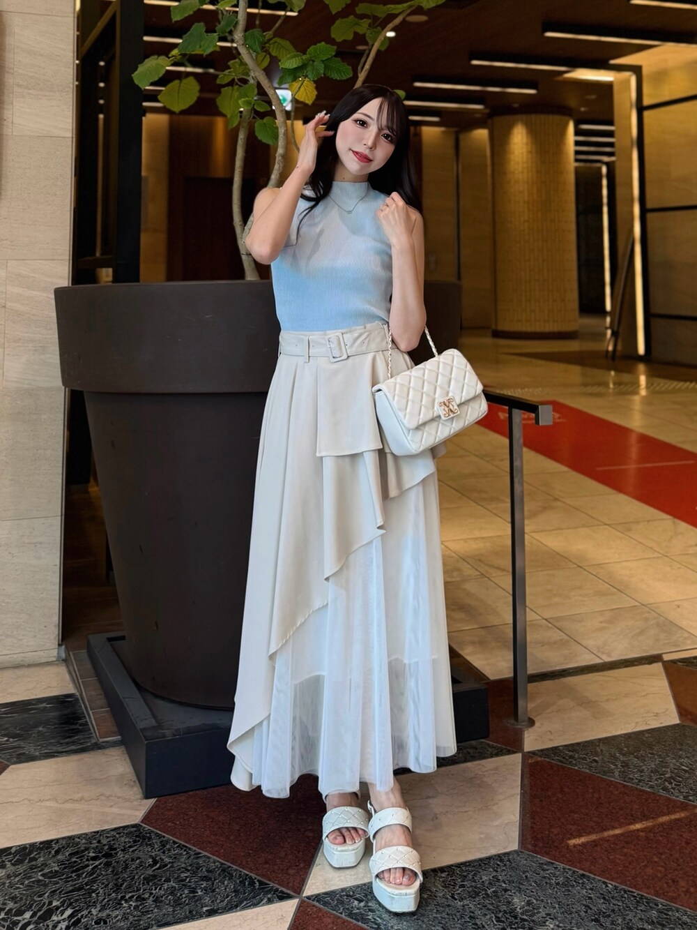 ベージュ系のスカート、ブルー系のニット/セーター、ホワイト系のショルダーバッグを着用したレディースの夏コーディネートの4枚目の写真