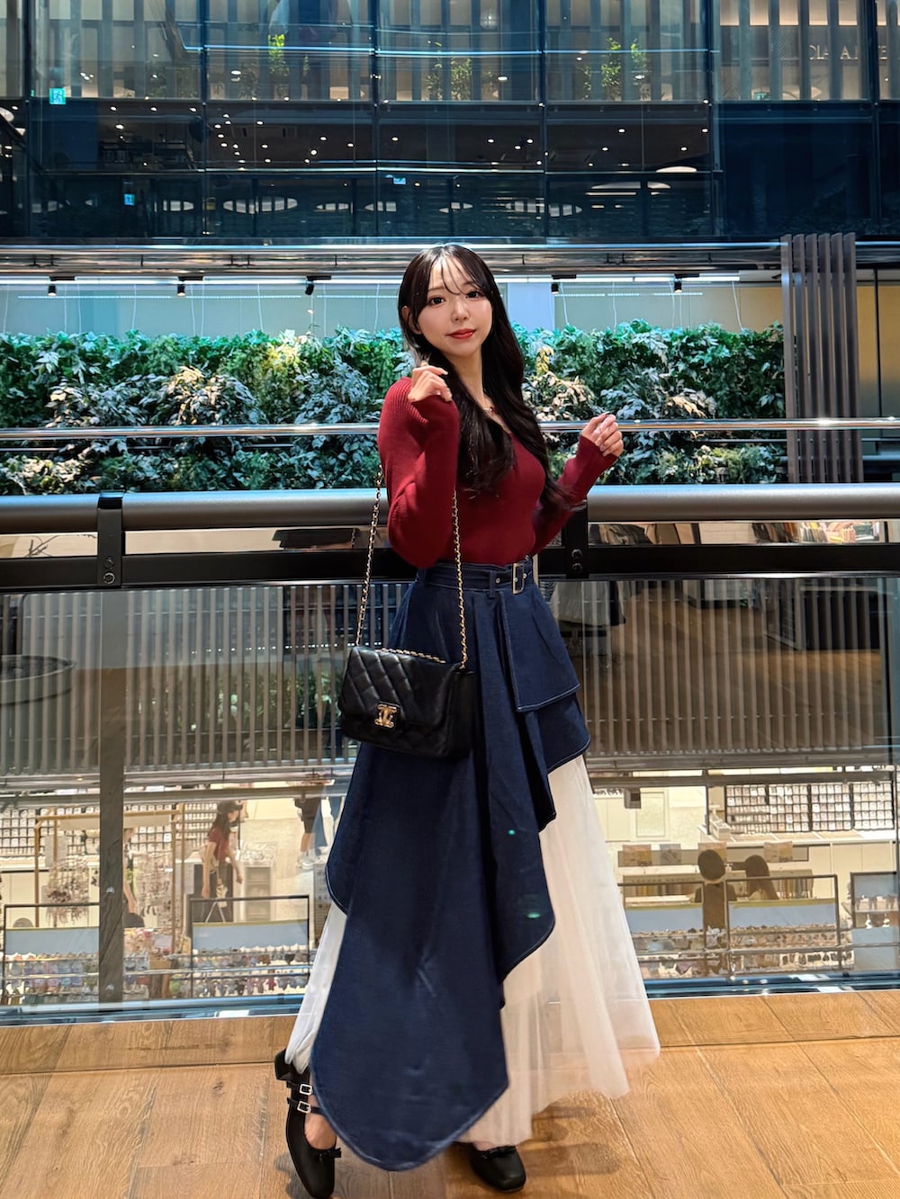 レッド系のニット/セーター、ブルー系のスカート、ブラック系のショルダーバッグを着用したレディースの秋コーディネートの3枚目の写真