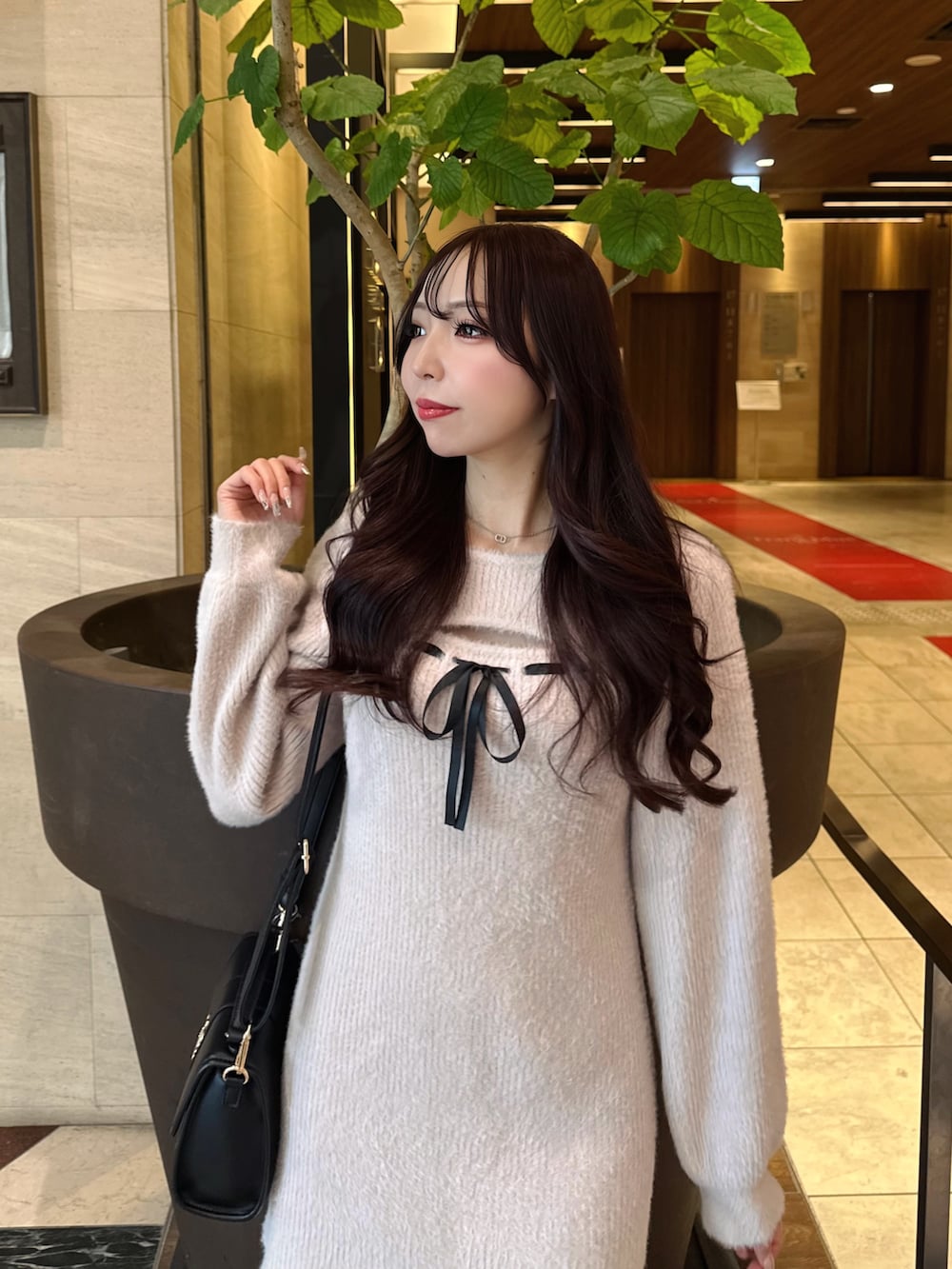 ピンク系のワンピース、ブラック系のハンドバッグを着用したレディースの冬コーディネートの3枚目の写真