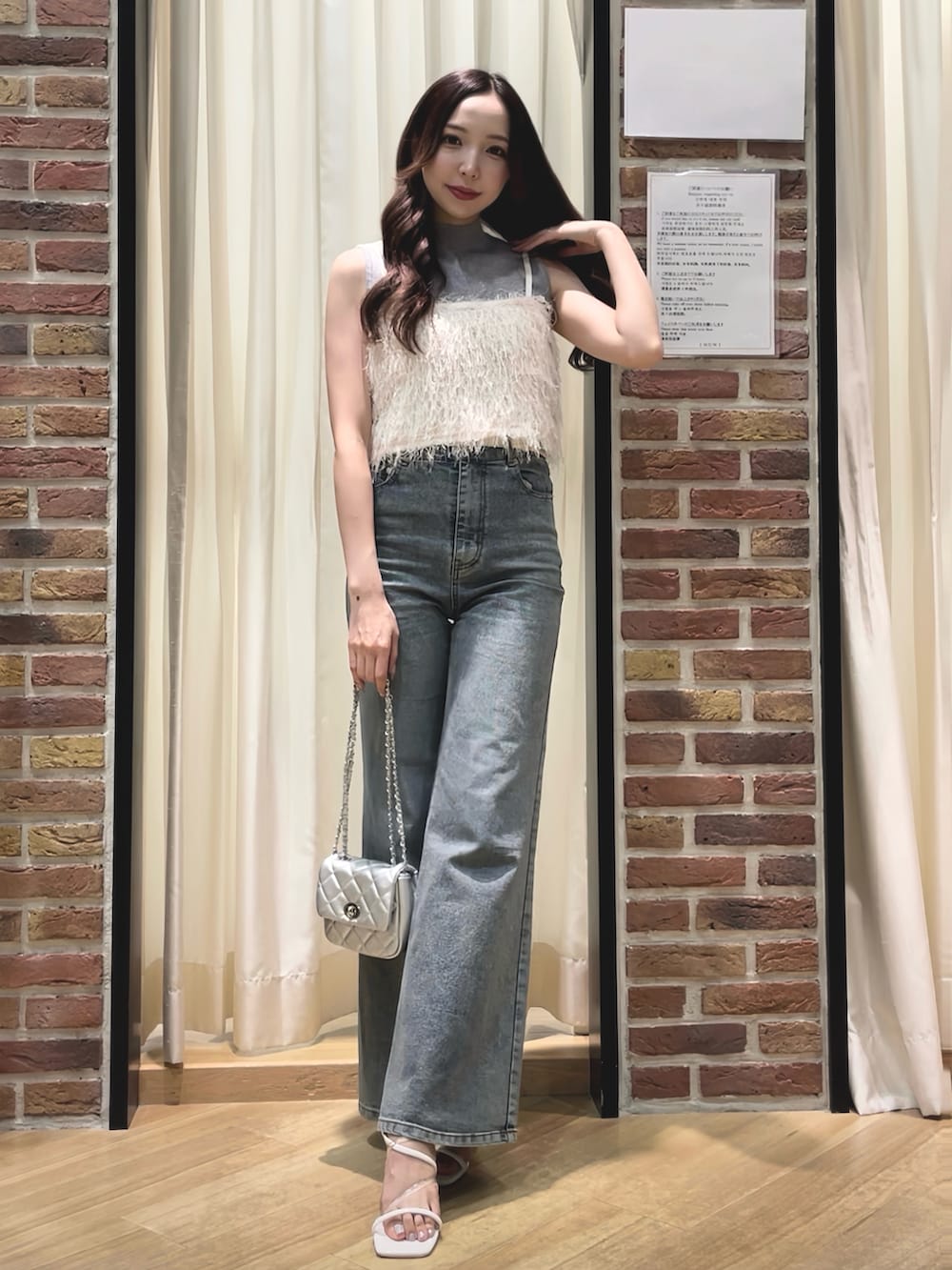 ホワイト系のベスト、グレー系のニット/セーター、ブルー系のデニムパンツを着用したレディースの夏コーディネートの3枚目の写真