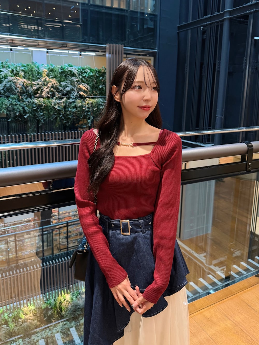 レッド系のニット/セーター、ブルー系のスカート、ブラック系のショルダーバッグを着用したレディースの秋コーディネートの4枚目の写真