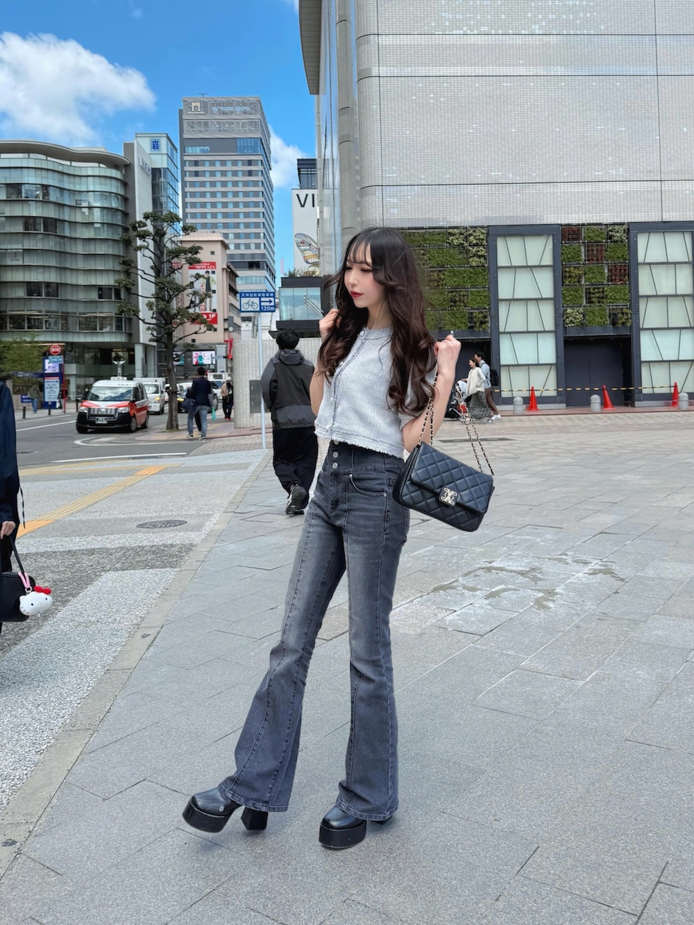 グレー系のノーカラージャケット、ブルー系のデニムパンツ、ブラック系のショルダーバッグを着用したレディースの春コーディネートの2枚目の写真