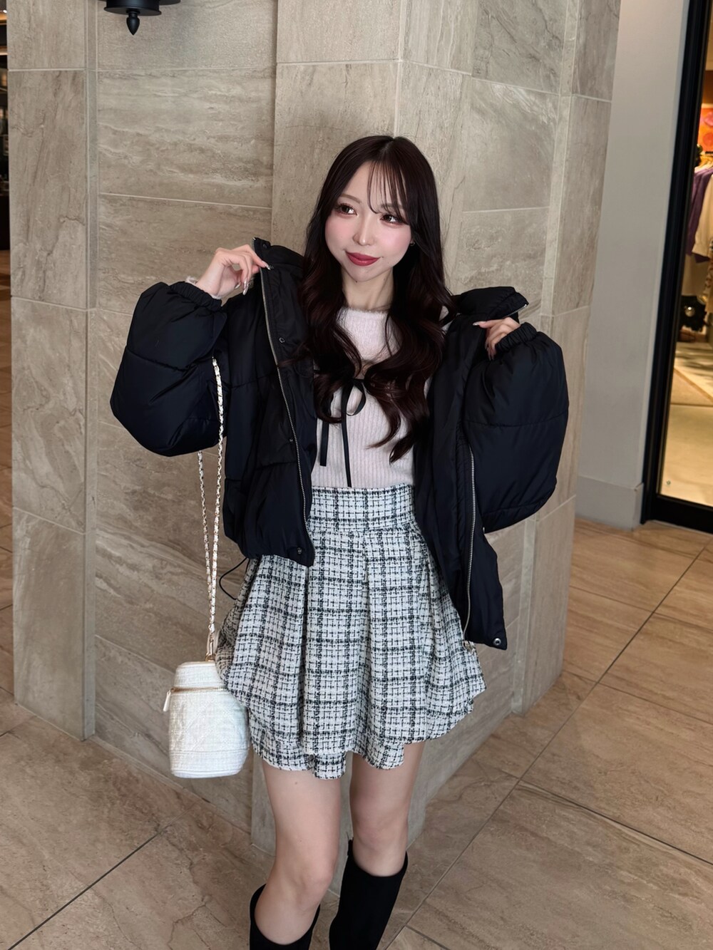 ブラック系のダウンジャケット/コート、ピンク系のニット/セーター、ホワイト系のスカートを着用したレディースの冬コーディネートの5枚目の写真