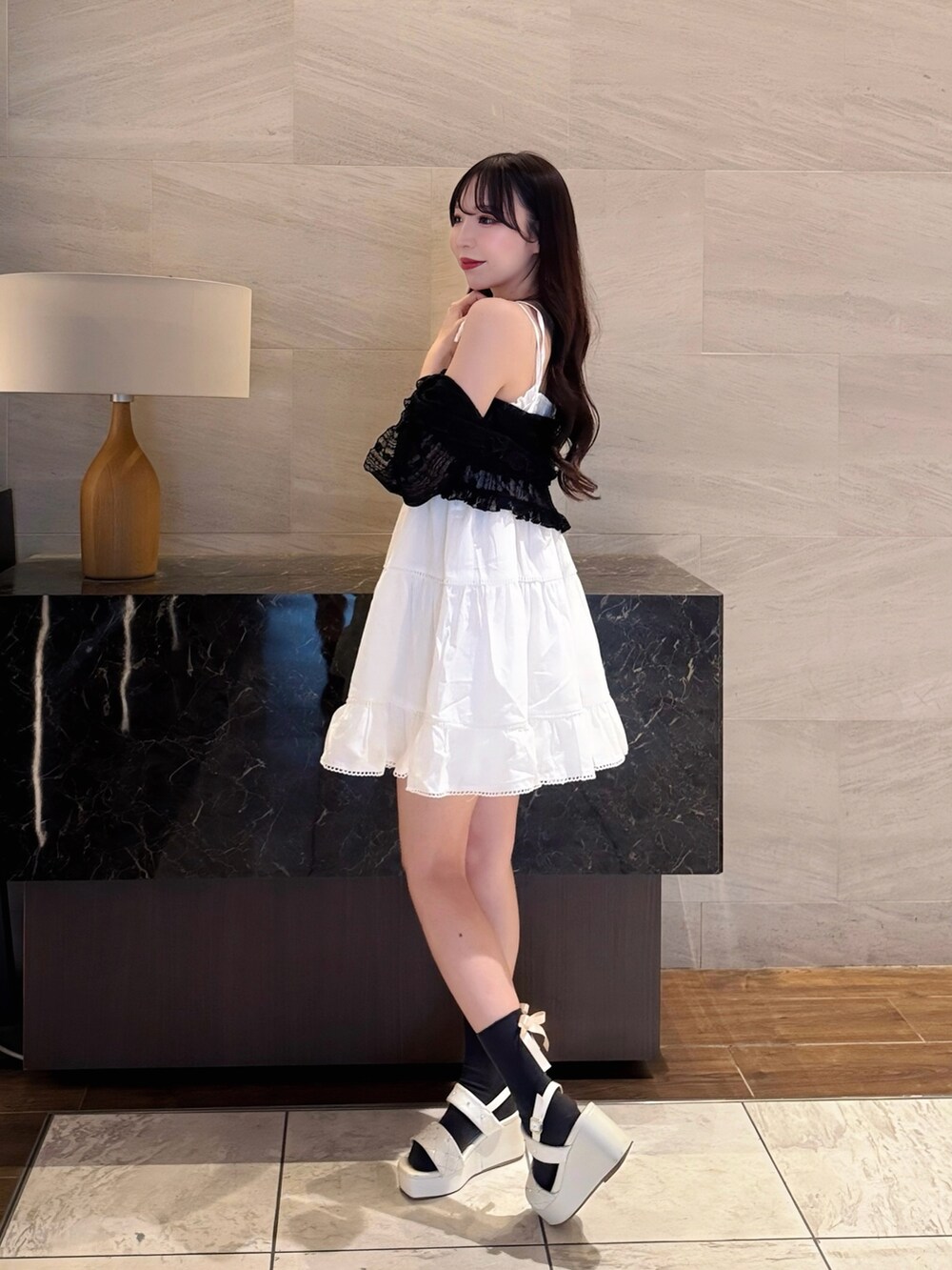 ホワイト系のワンピース、ブラック系のカーディガン/ボレロ、ホワイト系のサンダルを着用したレディースの夏コーディネートの4枚目の写真