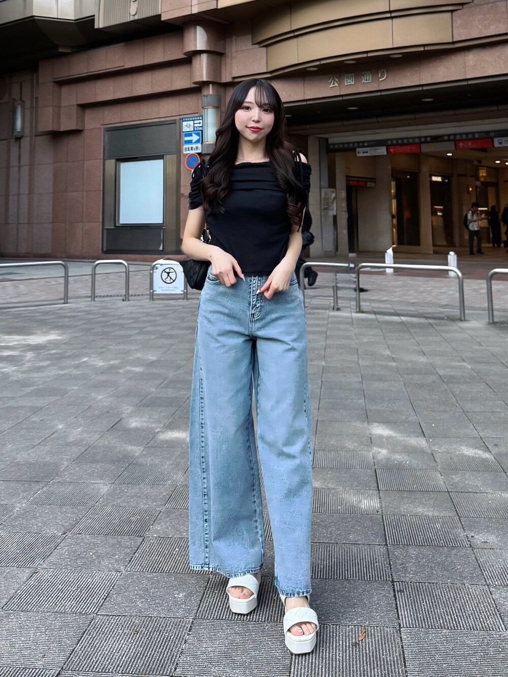 ブルー系のデニムパンツ、ブラック系のTシャツ/カットソー、ホワイト系のサンダルを着用したレディースの夏コーディネートの2枚目の写真