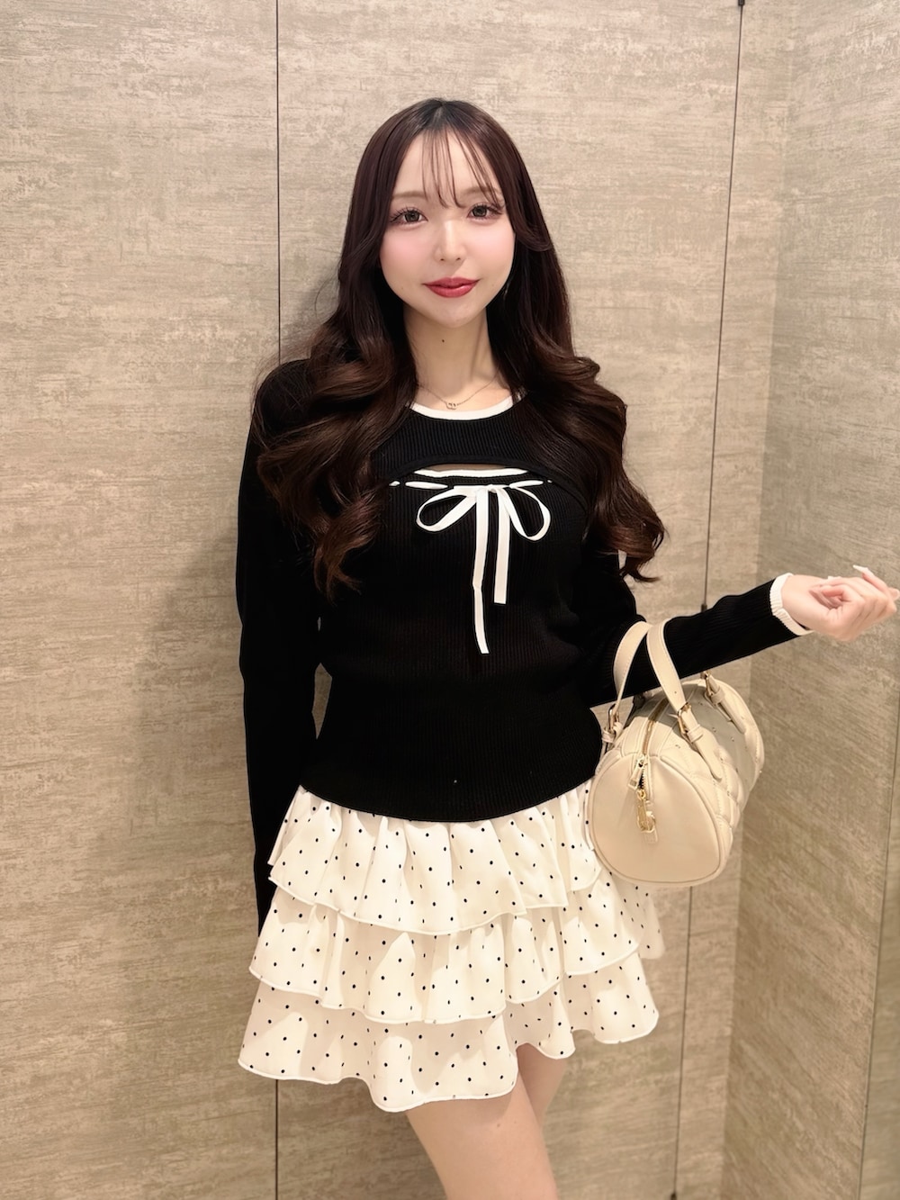 ホワイト系のボストンバッグ、ホワイト系のスカート、ブラック系のニット/セーターを着用したレディースの春コーディネートの3枚目の写真