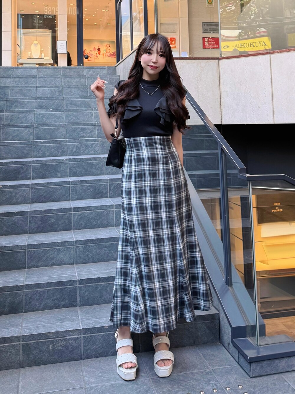 ブラック系のワンピース、ホワイト系のサンダル、ブラック系のショルダーバッグを着用したレディースの夏コーディネートの2枚目の写真