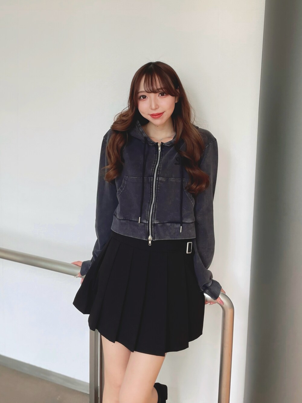 ブラック系のパーカー、ブラック系のスカートを着用したレディースの秋コーディネートの2枚目の写真