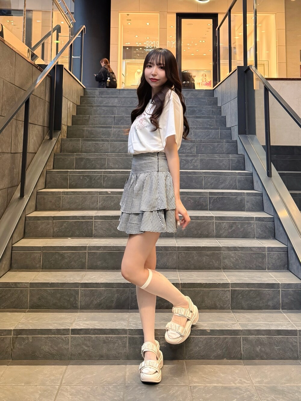 ホワイト系のTシャツ/カットソー、ブラック系のスカート、ホワイト系のサンダルを着用したレディースの春コーディネートの2枚目の写真