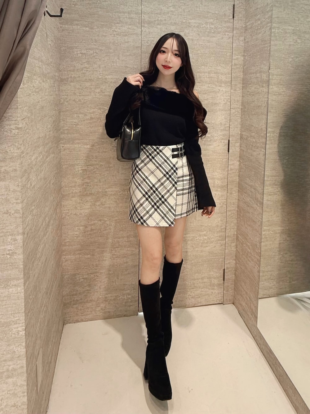 ブラック系のニット/セーター、ホワイト系のスカート、ブラック系のハンドバッグを着用したレディースの秋コーディネートの2枚目の写真