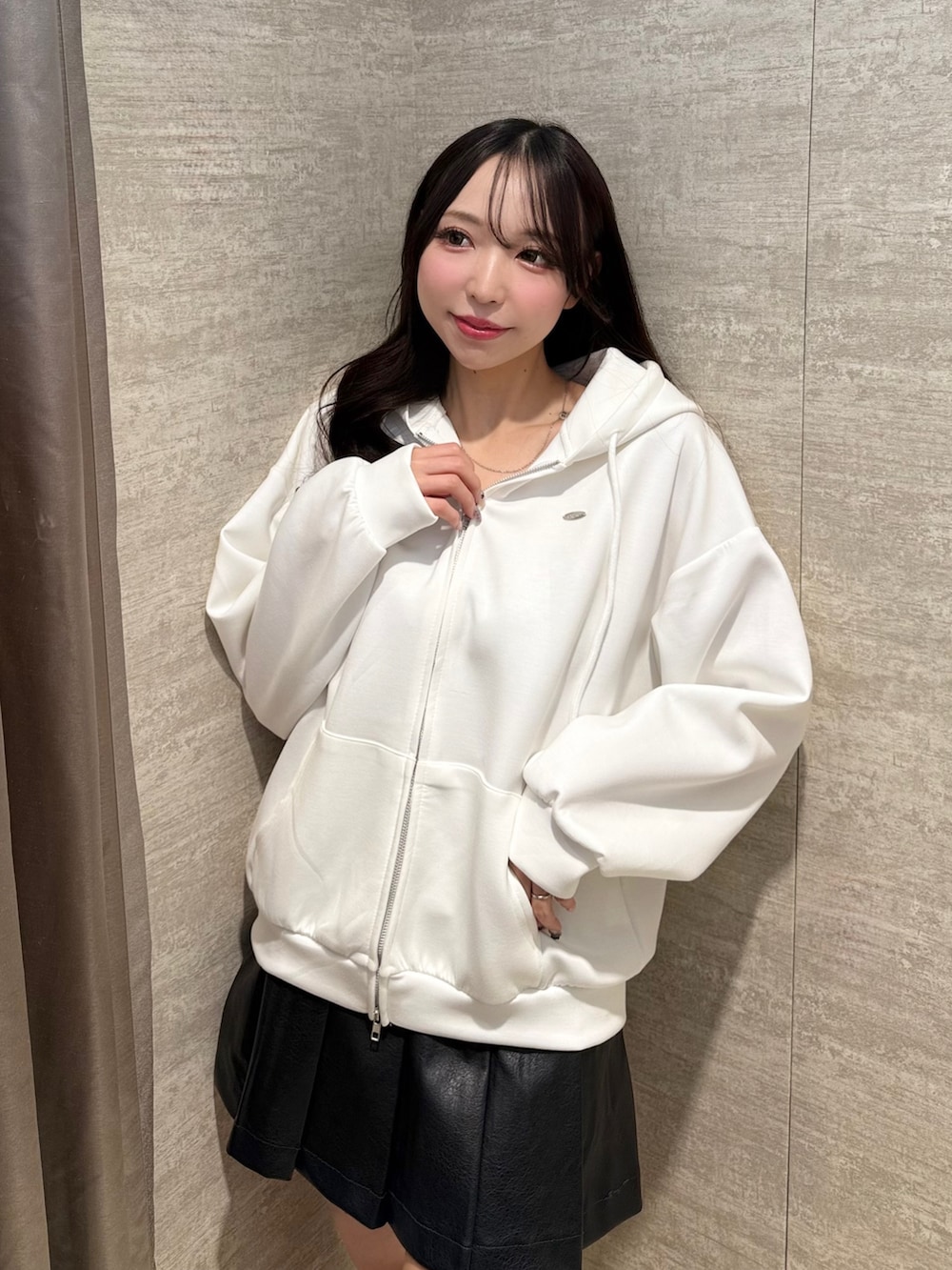 ホワイト系のパーカー、ブラック系のスカート、ベージュ系のブーツを着用したレディースの秋コーディネートの3枚目の写真