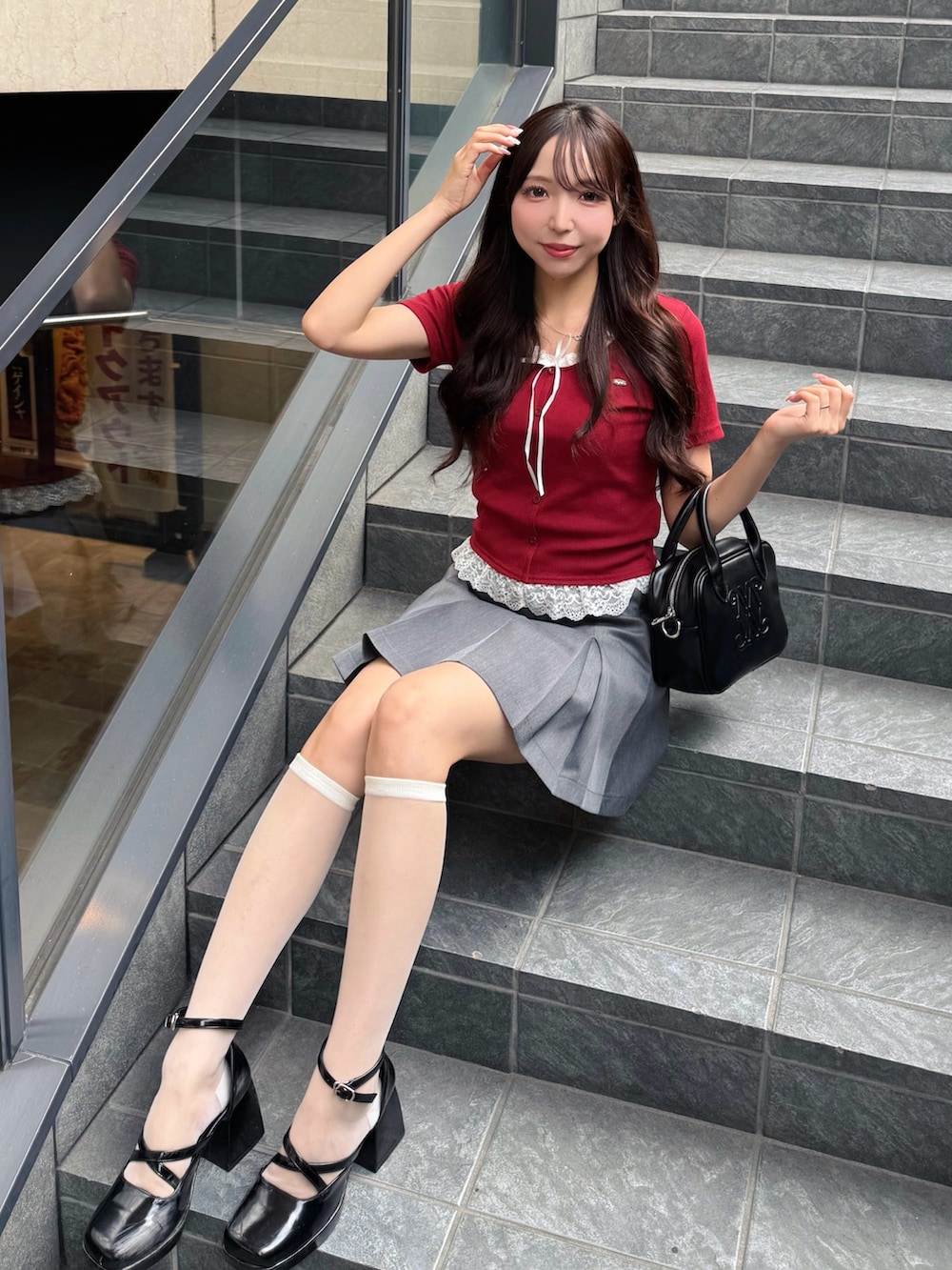 レッド系のTシャツ/カットソー、グレー系のスカート、ブラック系のハンドバッグを着用したレディースの夏コーディネートの2枚目の写真