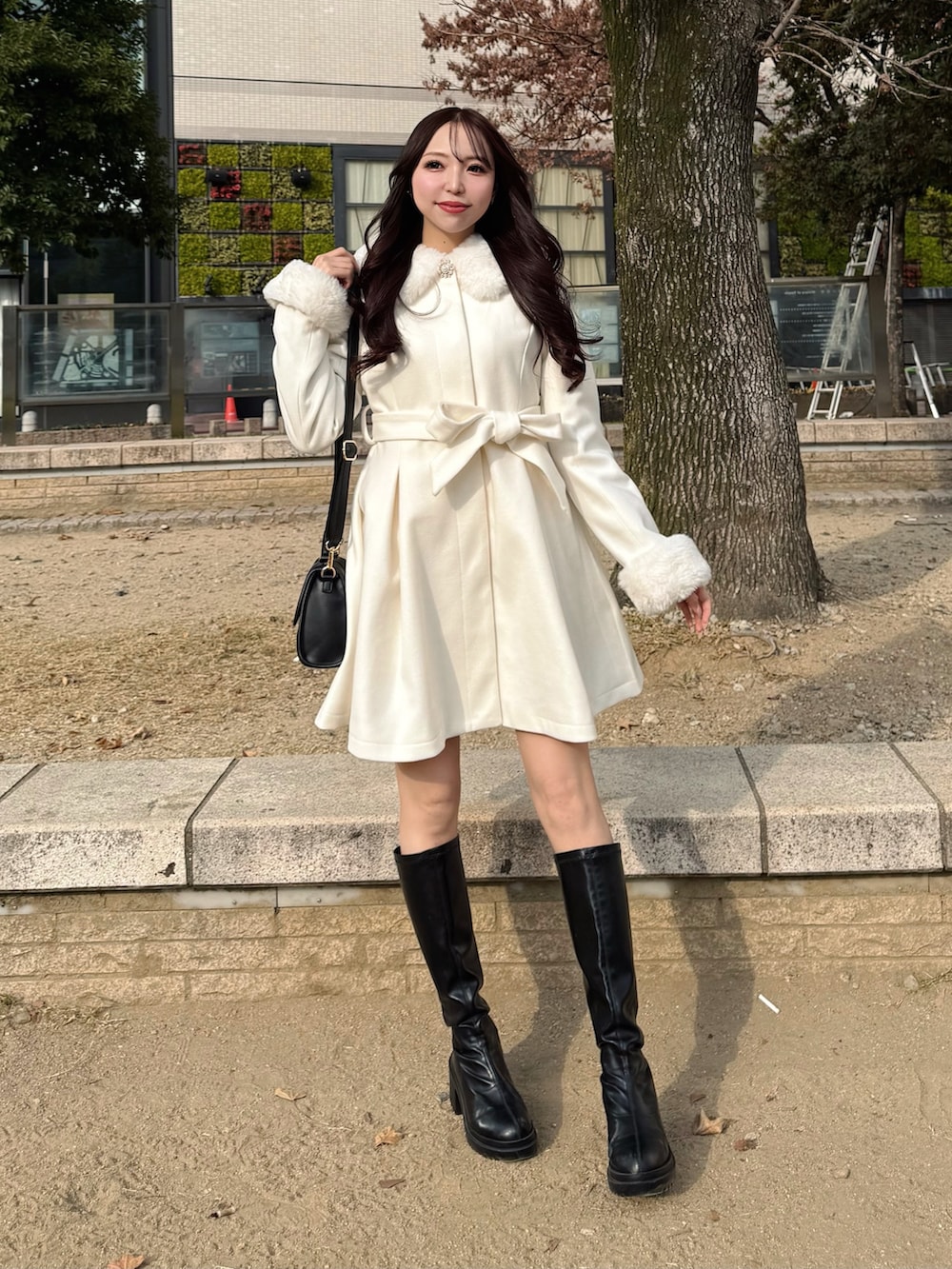 ブラック系のハンドバッグ、ホワイト系のその他アウターを着用したレディースの冬コーディネートの2枚目の写真