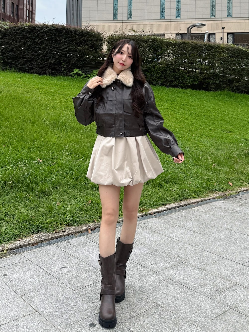 ブラック系のブルゾン、ベージュ系のスカート、ブラウン系のブーツを着用したレディースの秋コーディネートの2枚目の写真