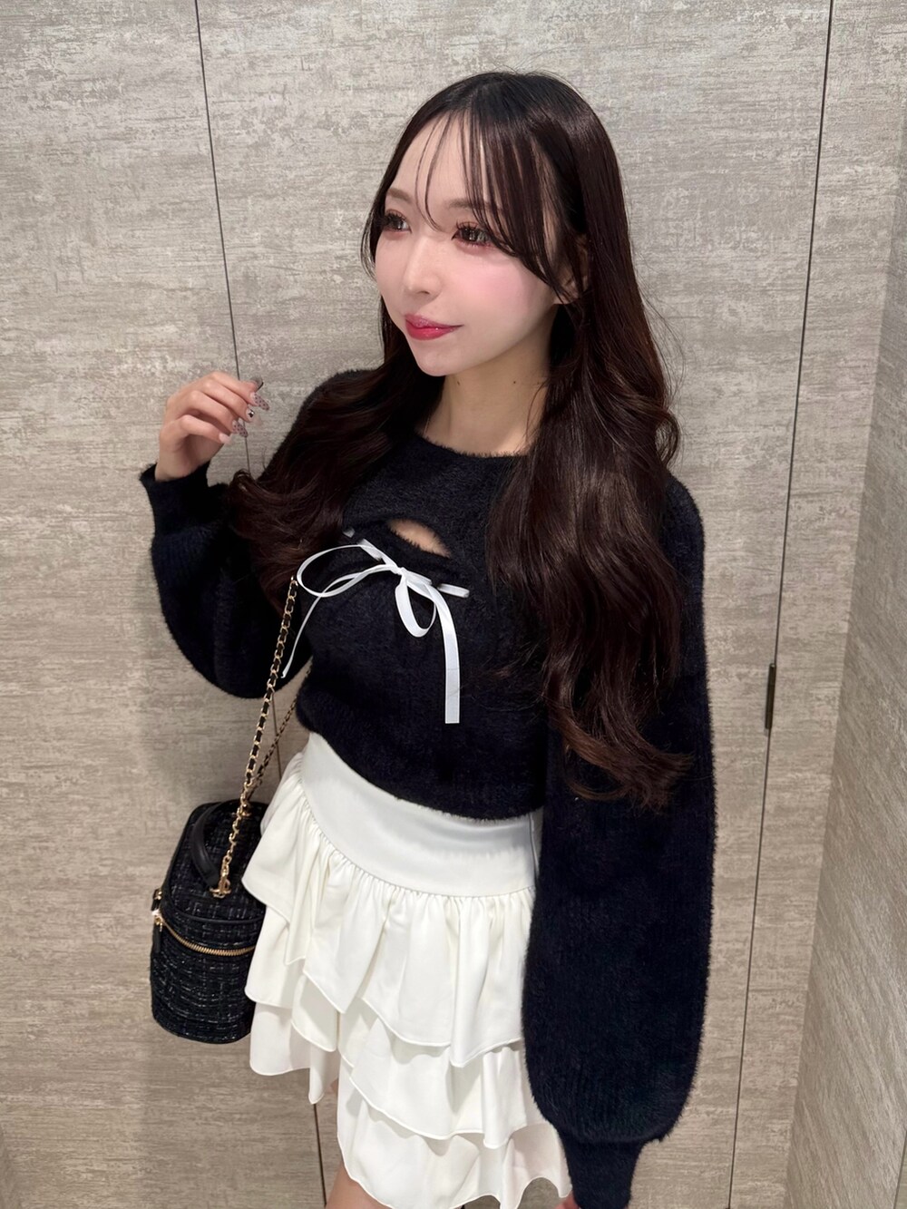 ブラック系のニット/セーター、ホワイト系のスカート、ブラック系のショルダーバッグを着用したレディースの秋コーディネートの4枚目の写真