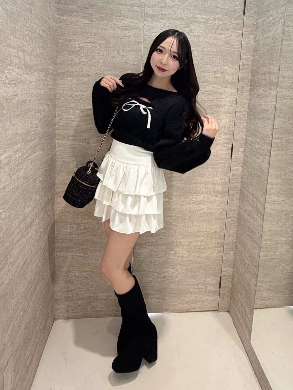 ブラック系のニット/セーター、ホワイト系のスカート、ブラック系のショルダーバッグを着用したレディースの秋コーディネートの2枚目の写真