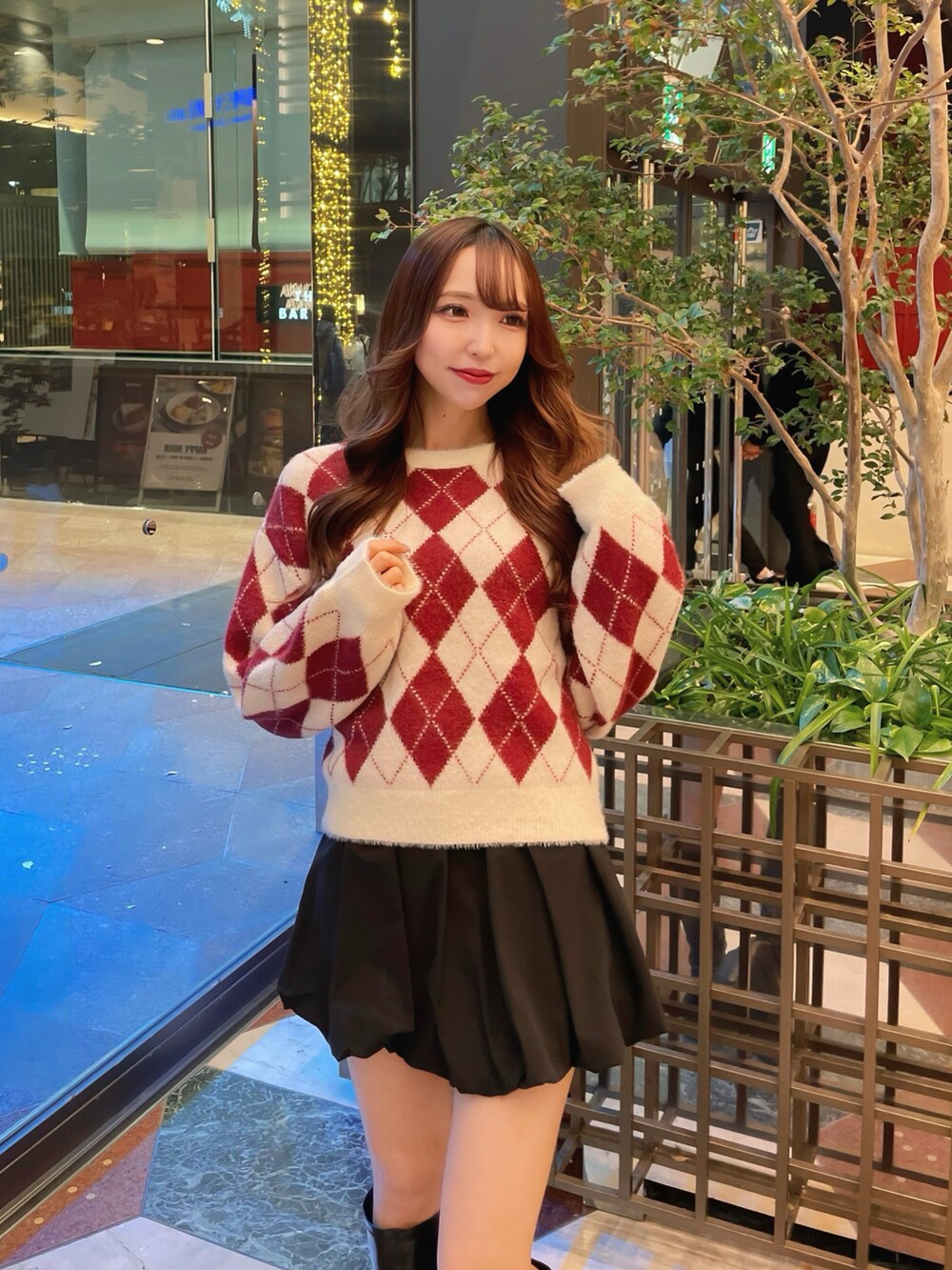 レッド系のニット/セーター、ブラック系のスカートを着用したレディースの冬コーディネートの3枚目の写真