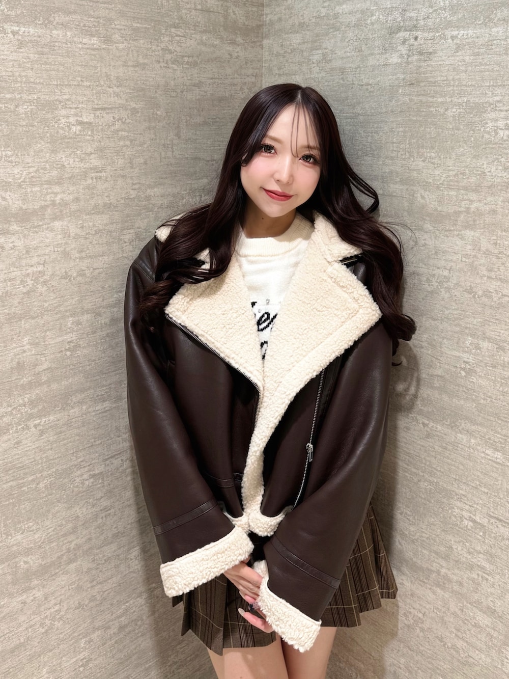 ブラウン系のムートンコート、ホワイト系のニット/セーター、ブラウン系のスカートを着用したレディースの秋コーディネートの4枚目の写真